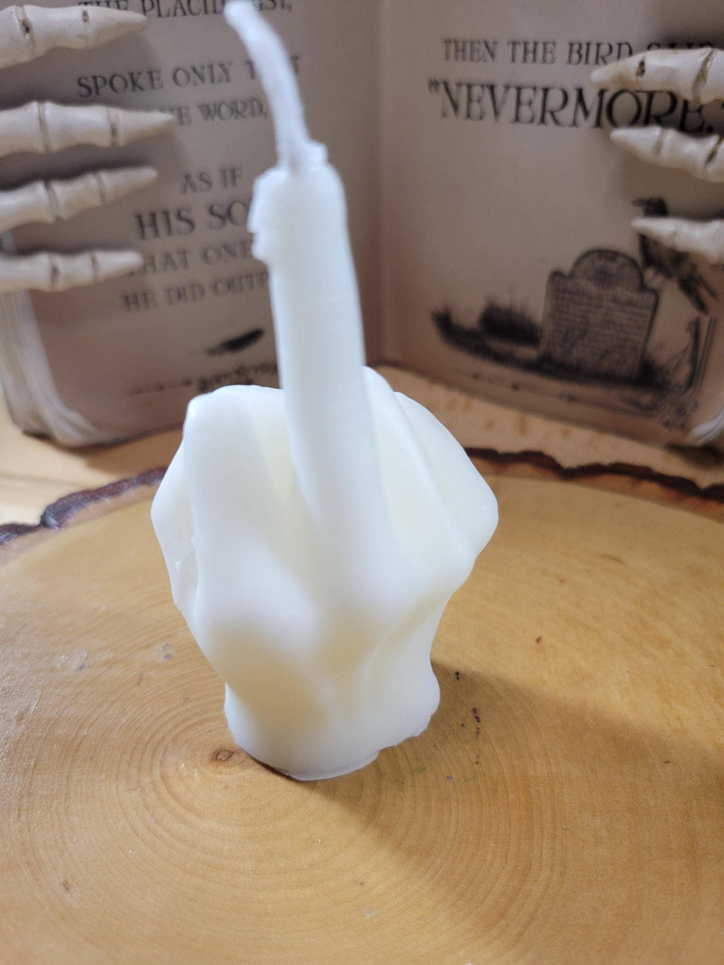 White ceramic sculpture of a face on a wooden surface with a book in the background.