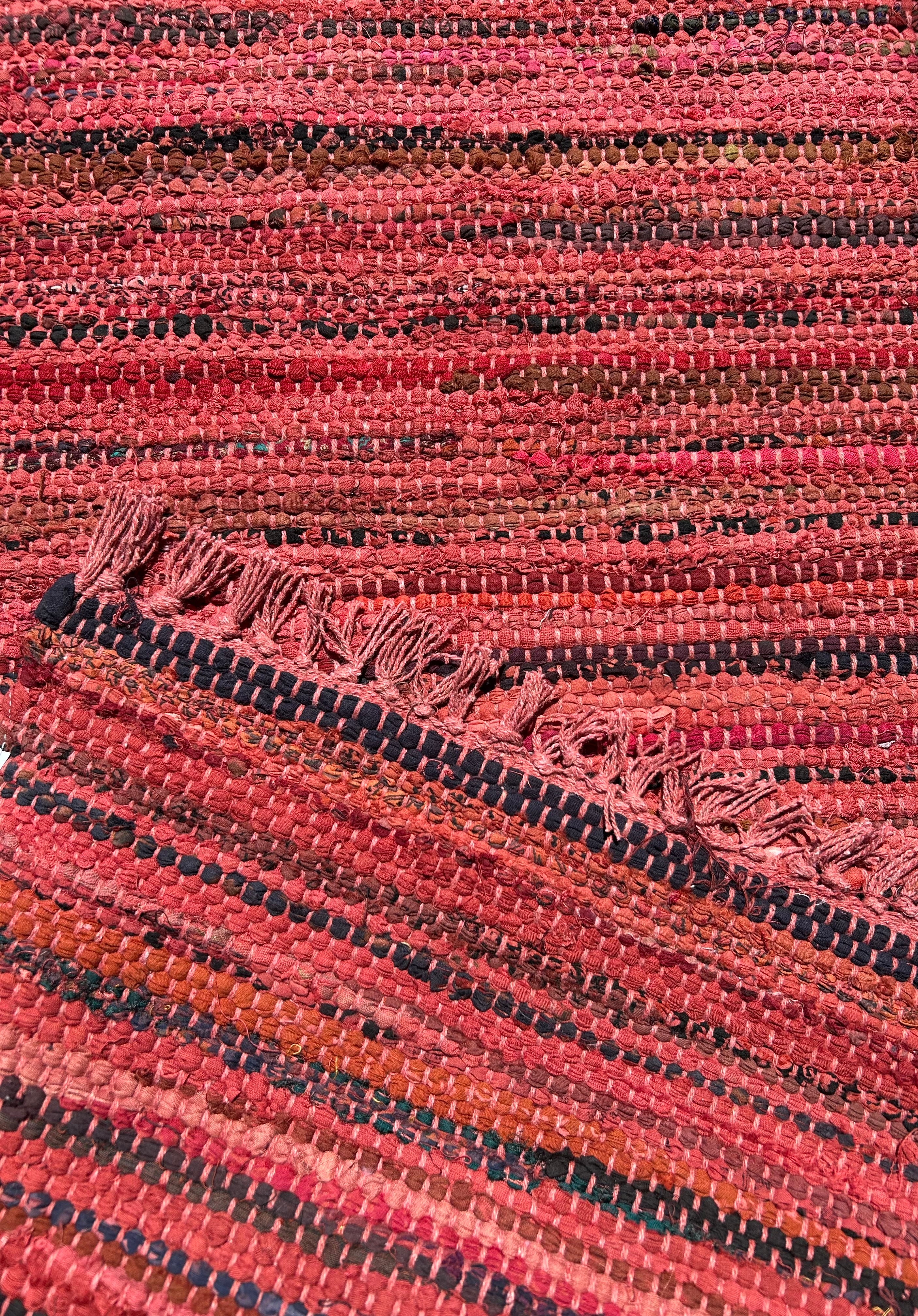 Close-up of a textured red rug with a subtle pattern showing front same as back