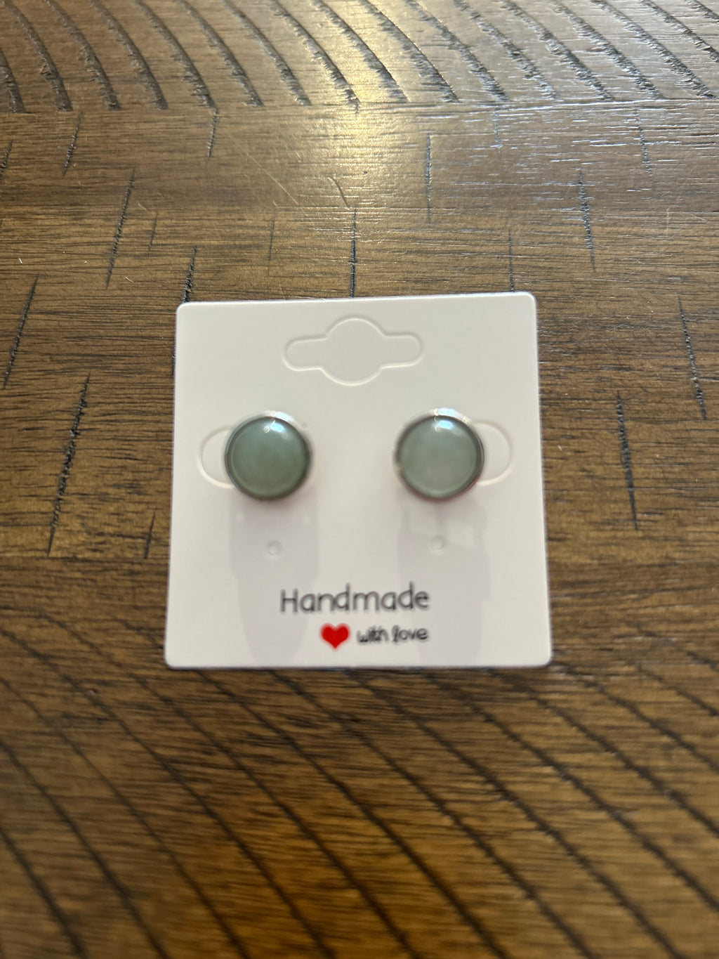 Pair of round earrings on a 'Handmade with Love' card on a wooden surface