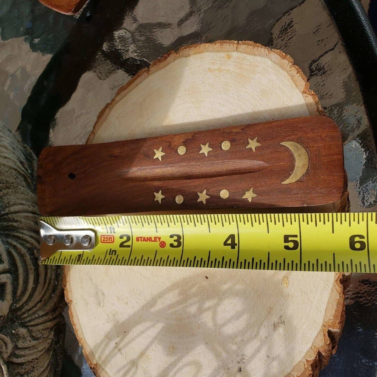 Wooden tool with star and moon designs on a circular wooden block, measured by a Stanley tape measure.