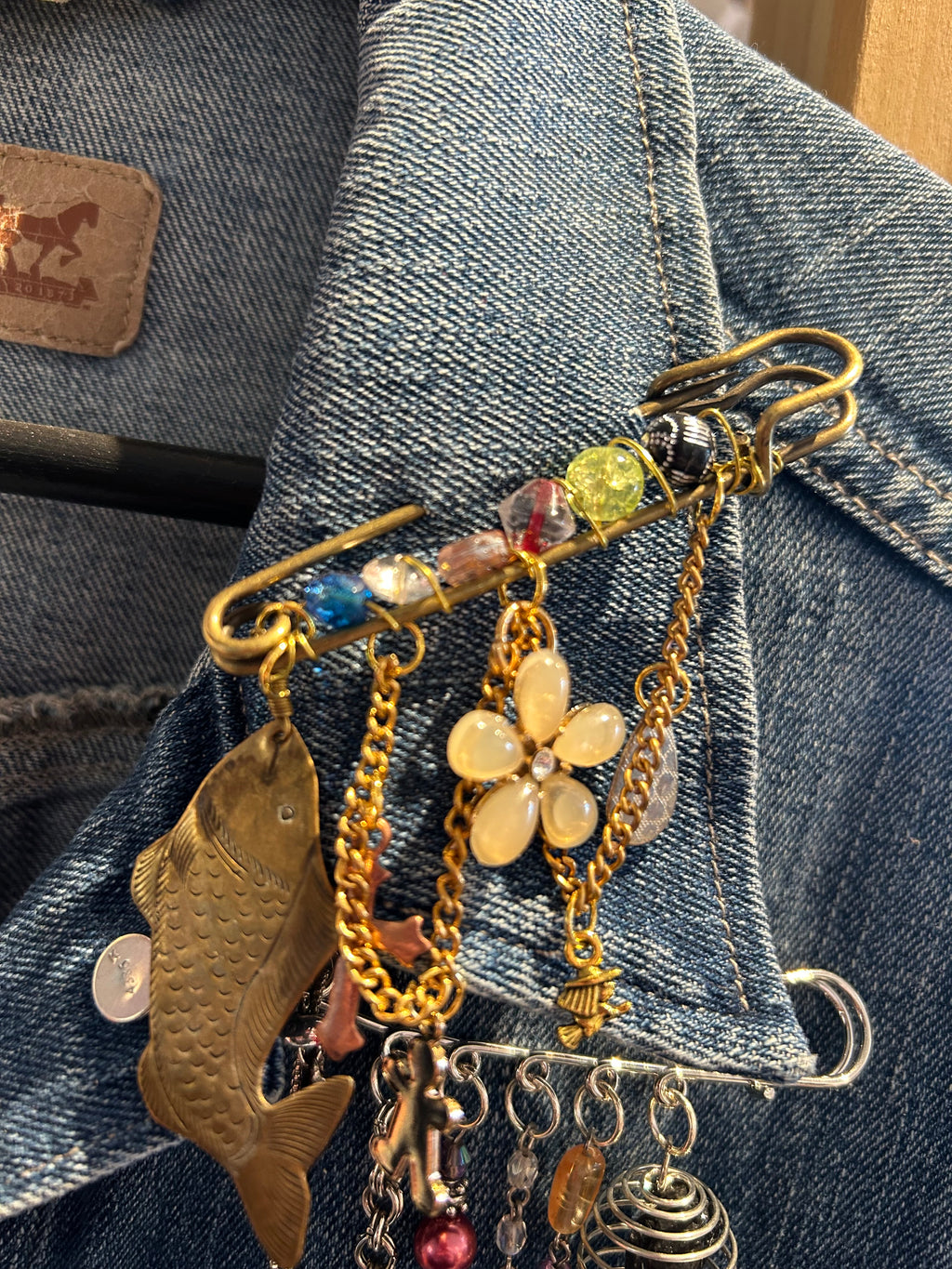 Decorative brooch with floral and fish designs on a denim background