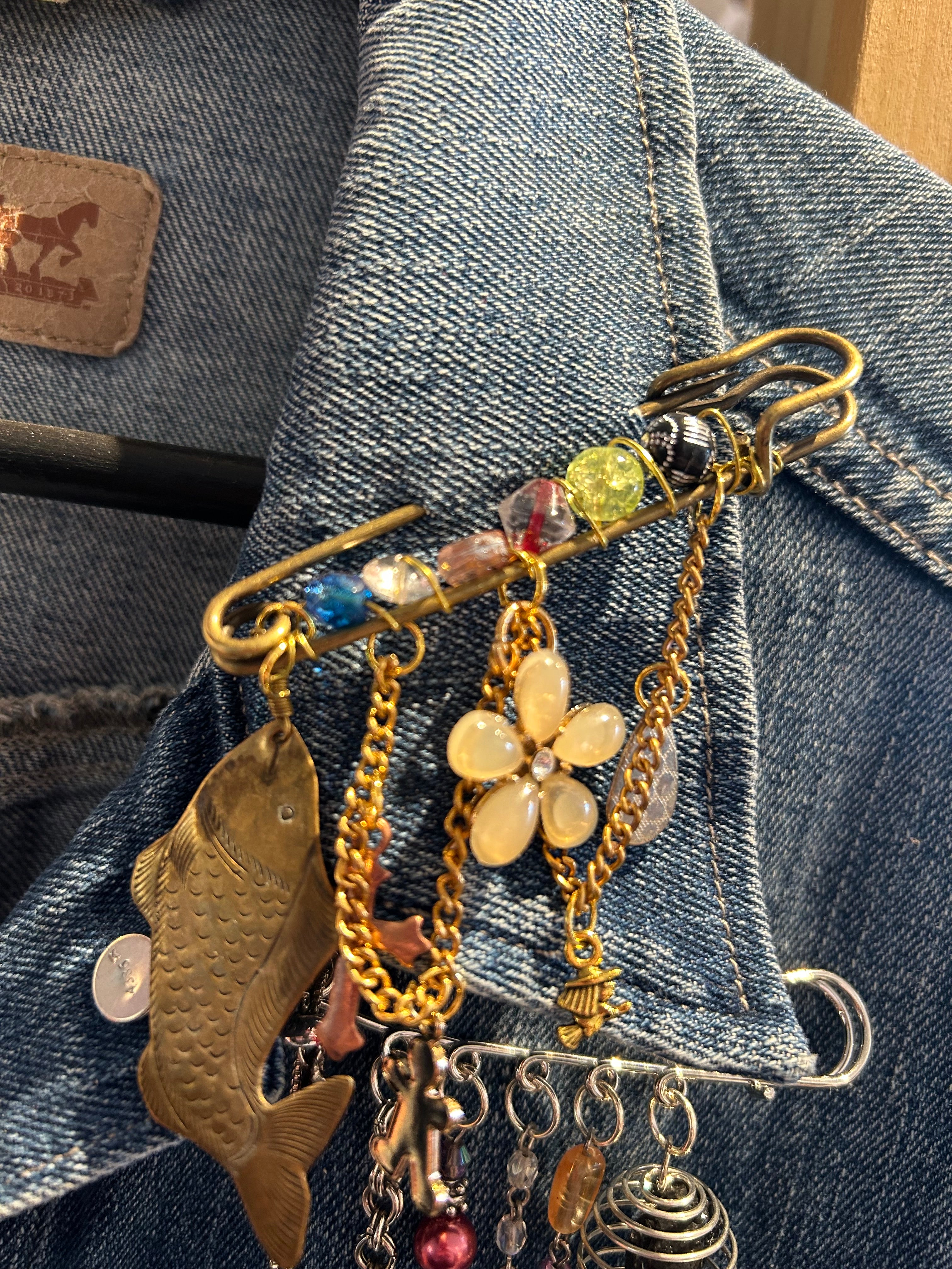 Decorative brooch with floral and fish designs on a denim background