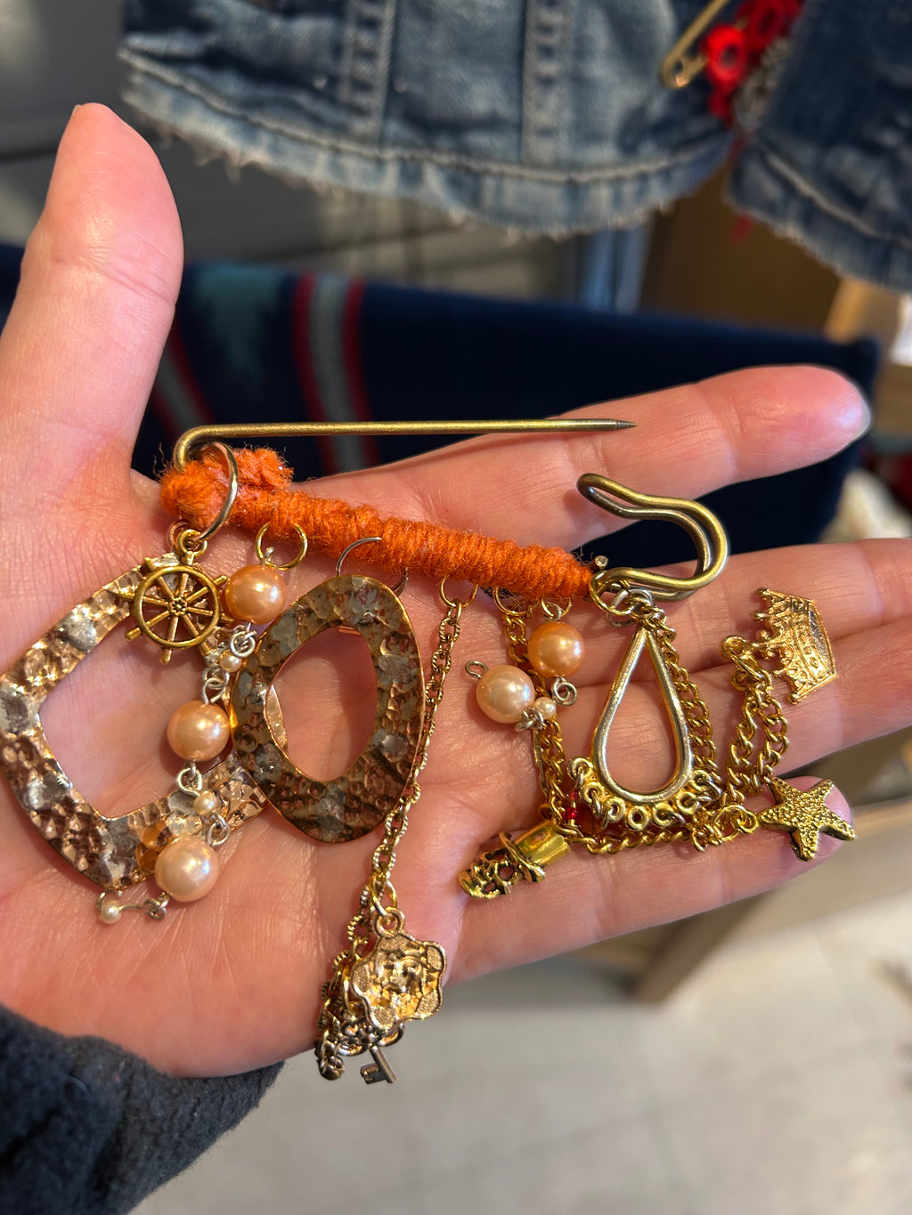 Hand holding various pieces of jewelry including gold chains, pendants, and beads.