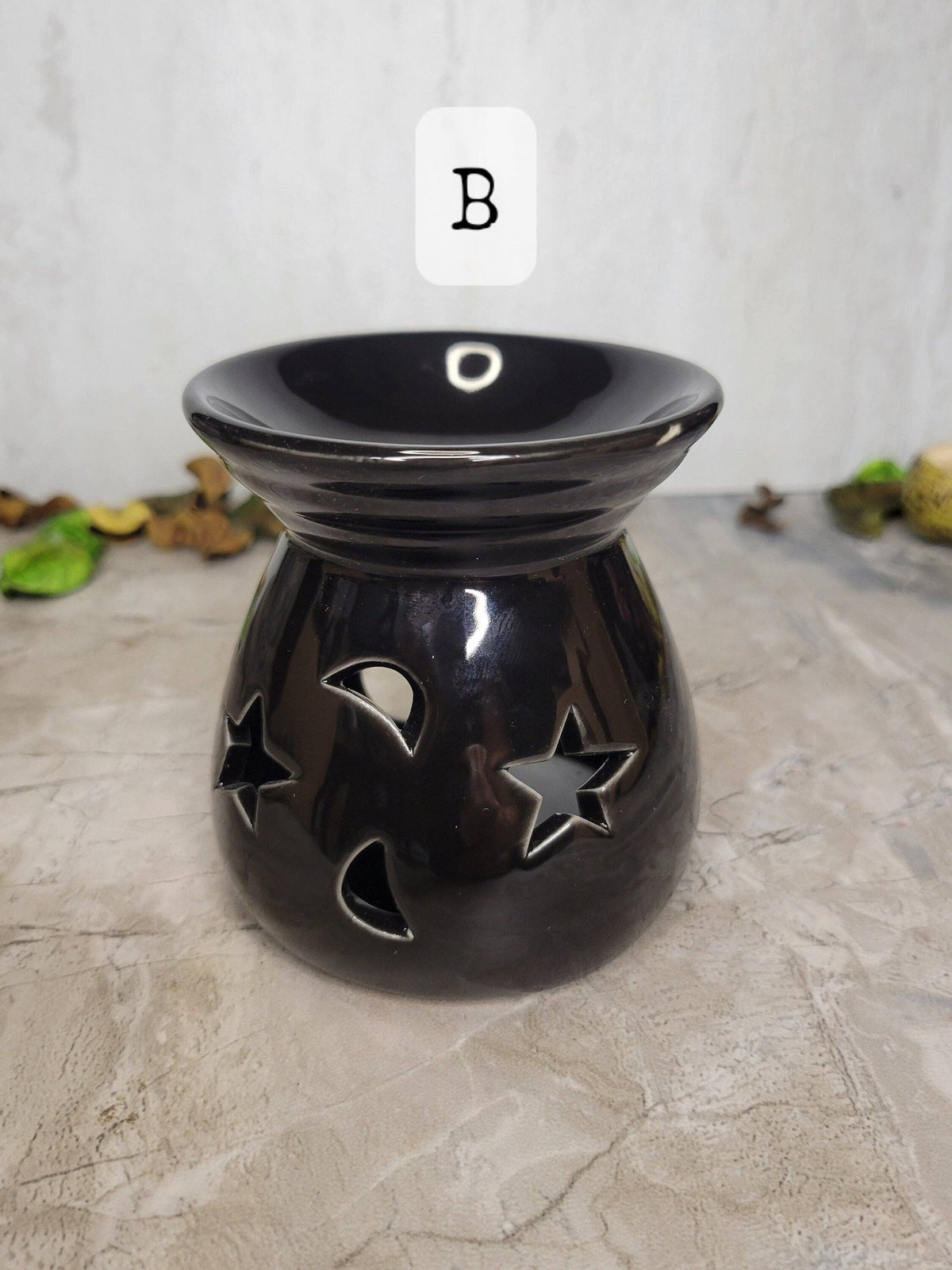 Black ceramic oil burner with star and moon designs on a textured surface.