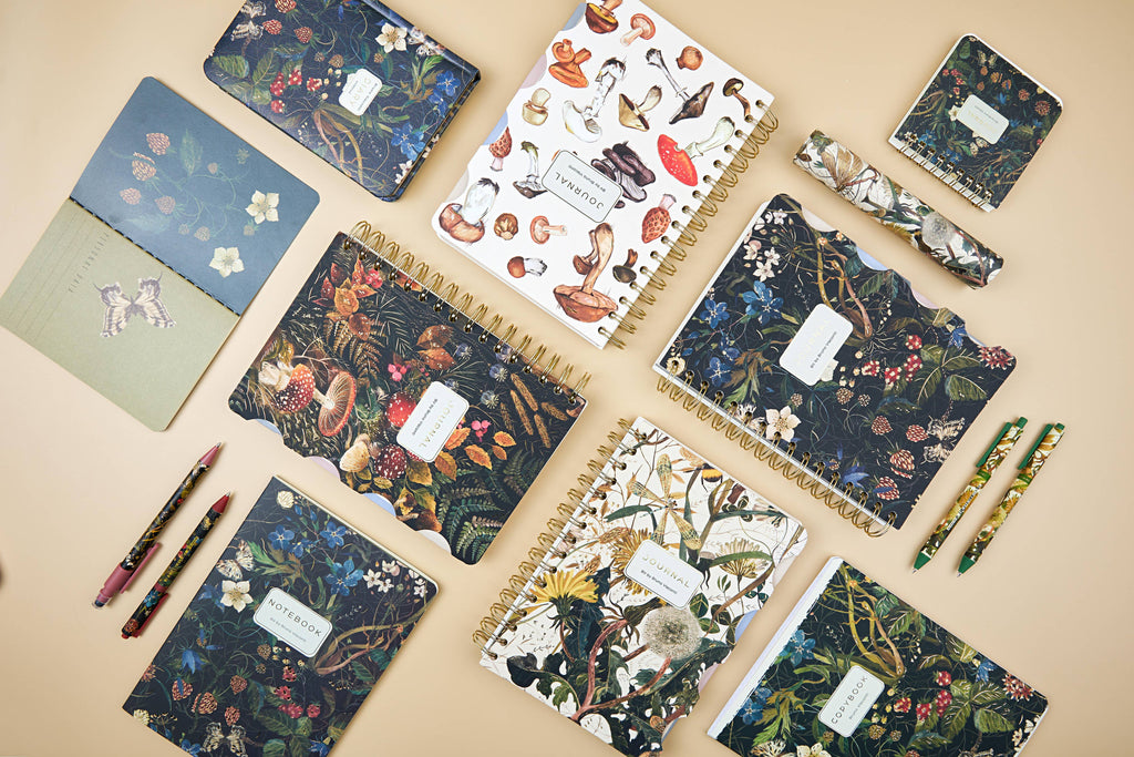 Collection of notebooks with floral and nature-themed designs on a beige surface.