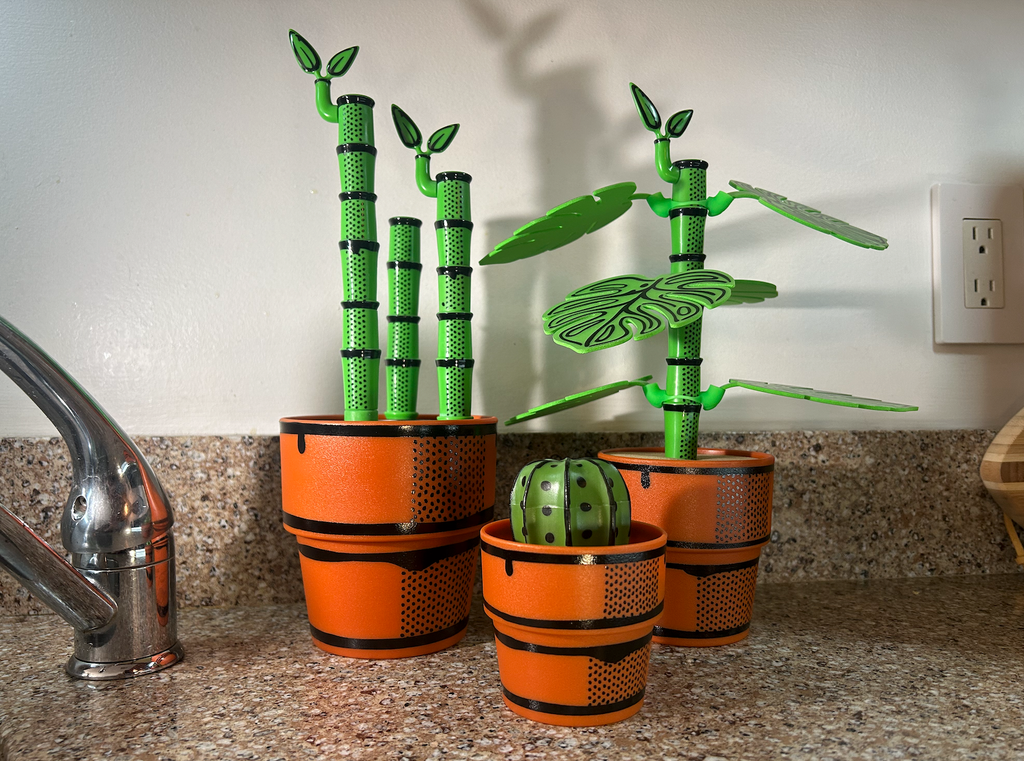 Decorative green plants that are bottle brushes or drink coasters in orange pots on a kitchen counter.