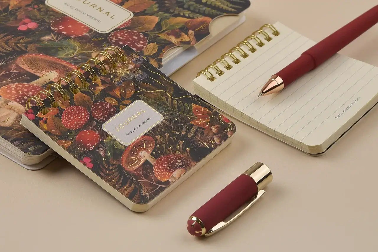 Mini Notebook with a mushroom design cover, pen, and decorative item on a beige surface