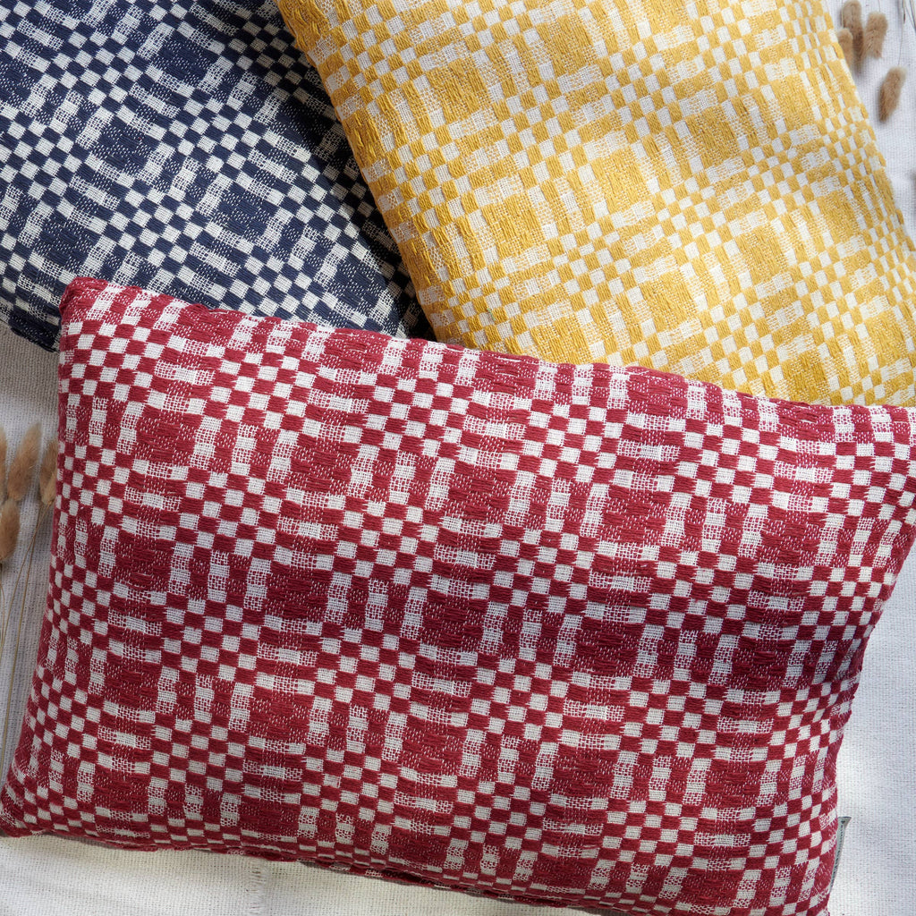 Three fabric pillows with checkered patterns in red, yellow, and blue.
