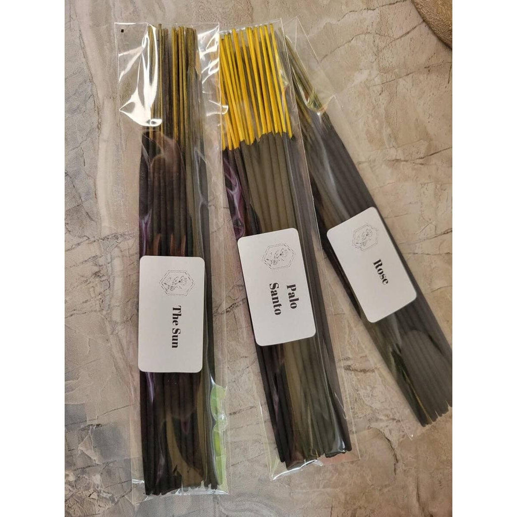 Three bundles of incense sticks with labels on a textured surface