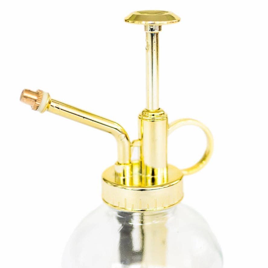 Gold and clear spray bottle on a white background