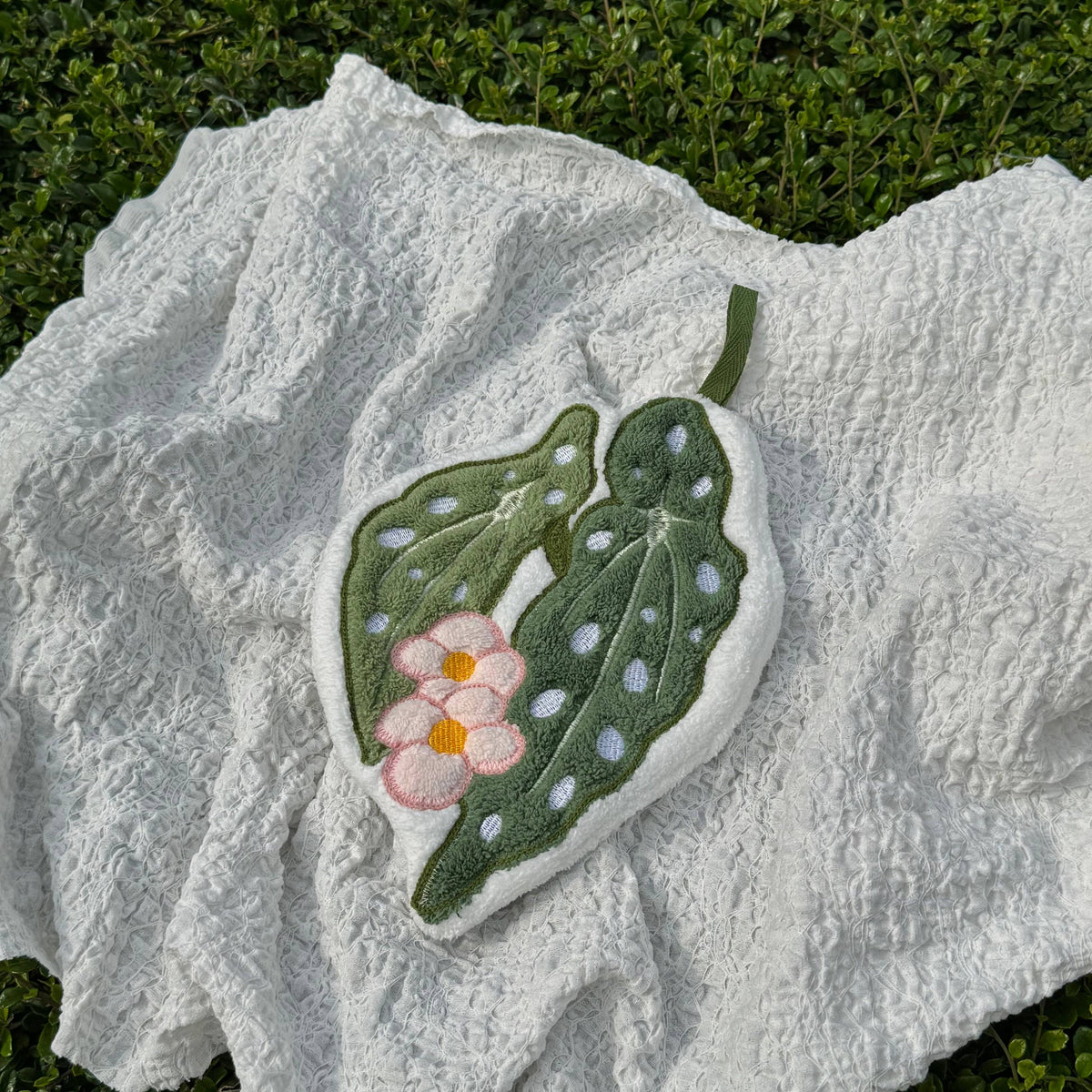 Decorative hand towel with floral and leaf design on a textured surface