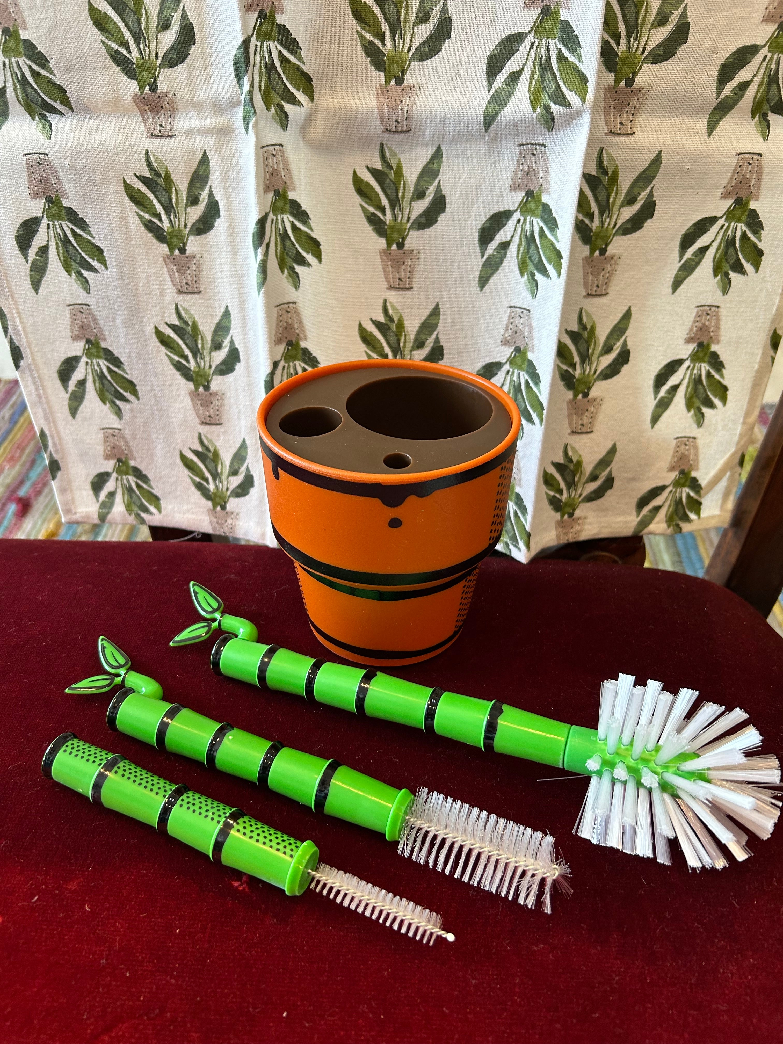 Green Bamboo Looking Bottle Brush Set with orange plant pot looking base with a Peace Lily Tea Towel by Mahogany.