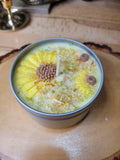 Sunflower-themed candle in a tin on a wooden surface