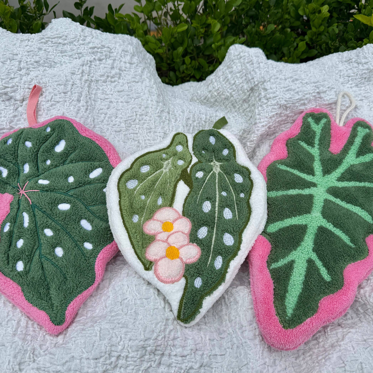 Decorative leaf-shaped hand towel with pink edges on a white towel