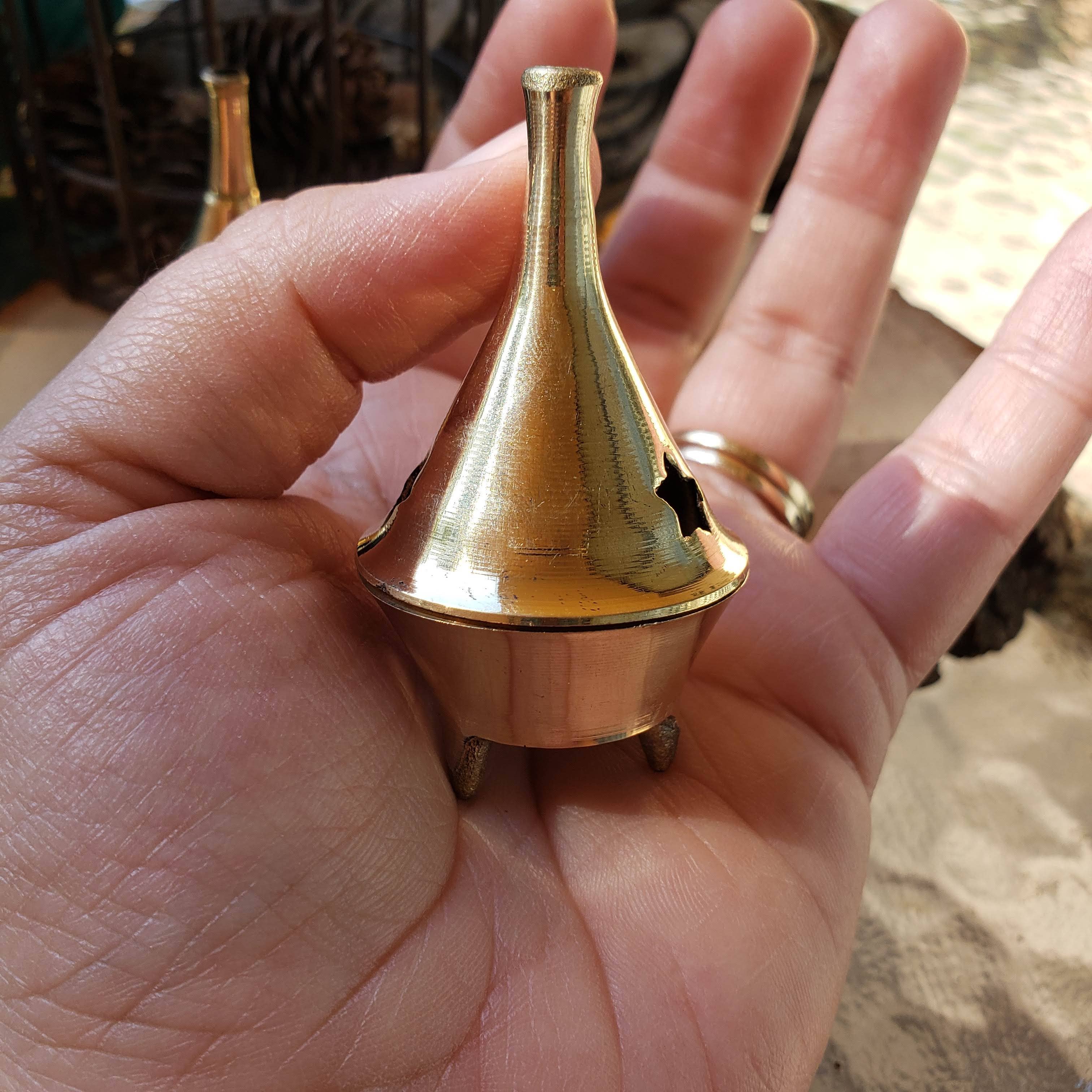 Hand holding a small brass incense with a blurred background