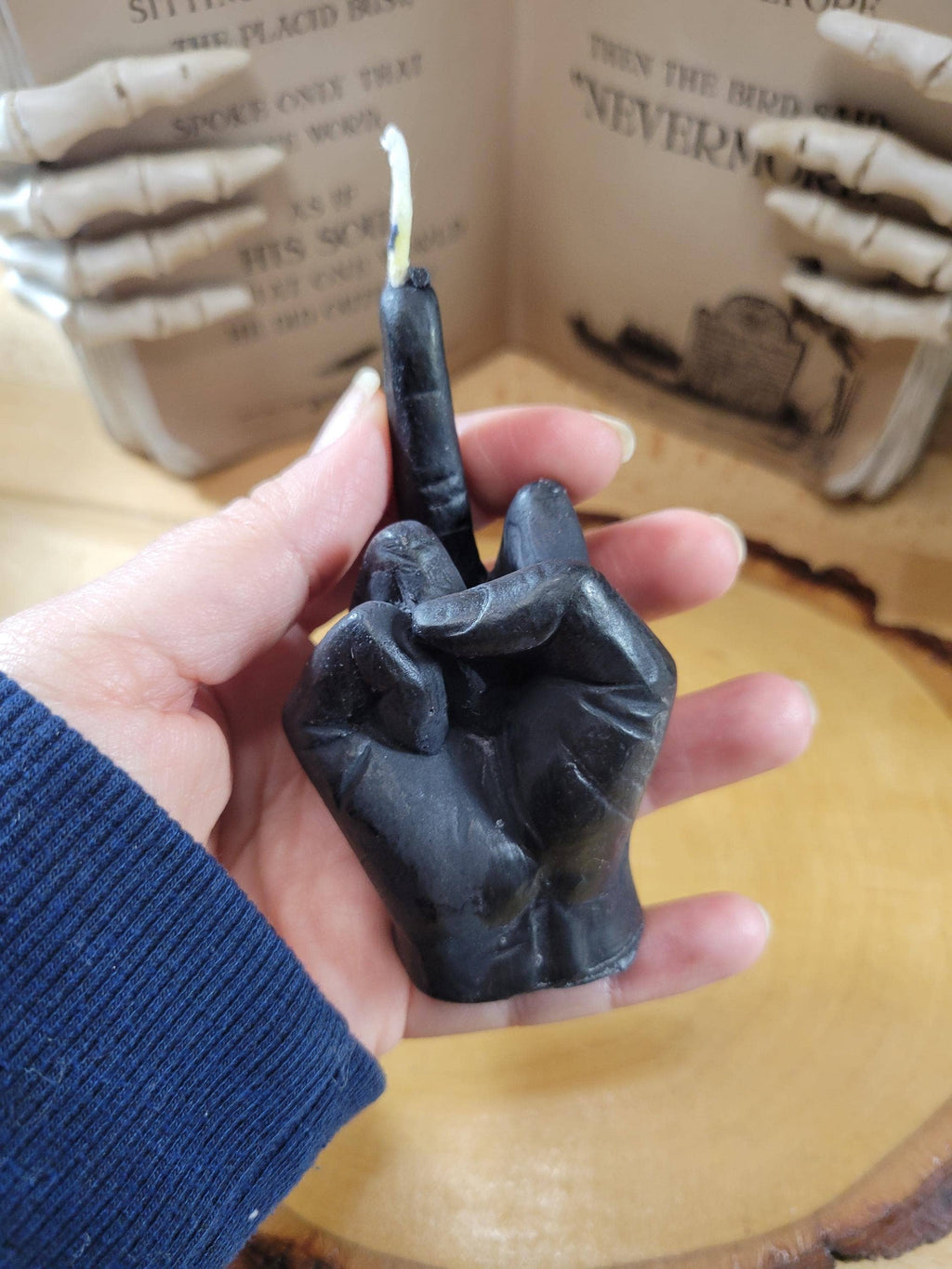 Hand holding a black hand-shaped candle with a blurred background