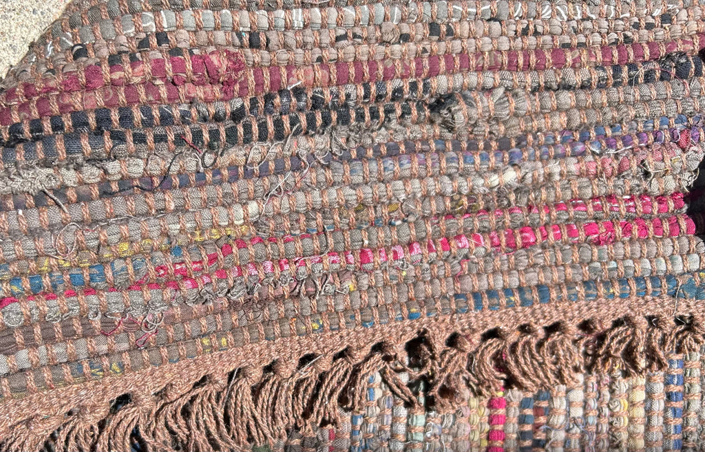 Close-up of a textured fabric with colorful patterns and fringes. Showing back same as front.