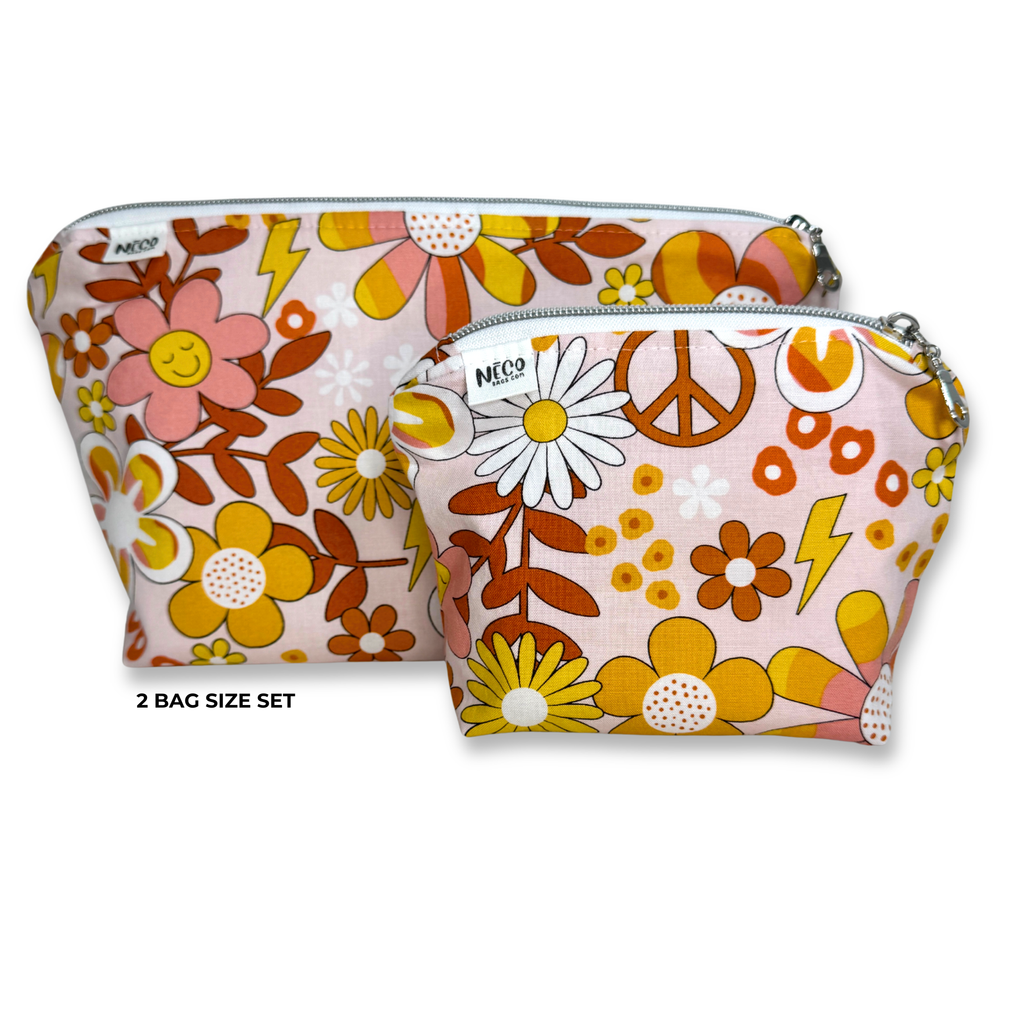 Two zippered cosmetic bags in a retro 70s floral print set against a plain white background. The set includes a larger pouch and a smaller pouch, both featuring a pink base with yellow, orange, and brown flowers, daisies, peace signs, and lightning bolts.