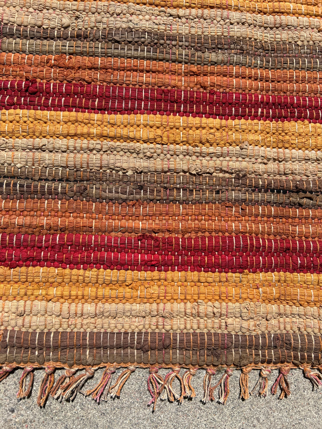 Textured woven mat with multicolored stripes on a gray background