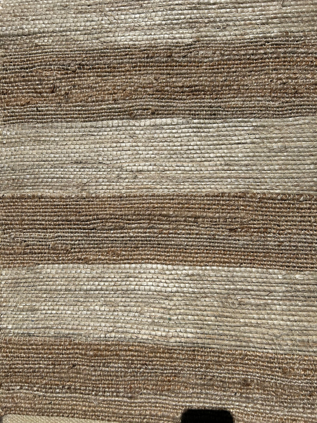 Close-up of a textured brown and beige hemp fabric rug