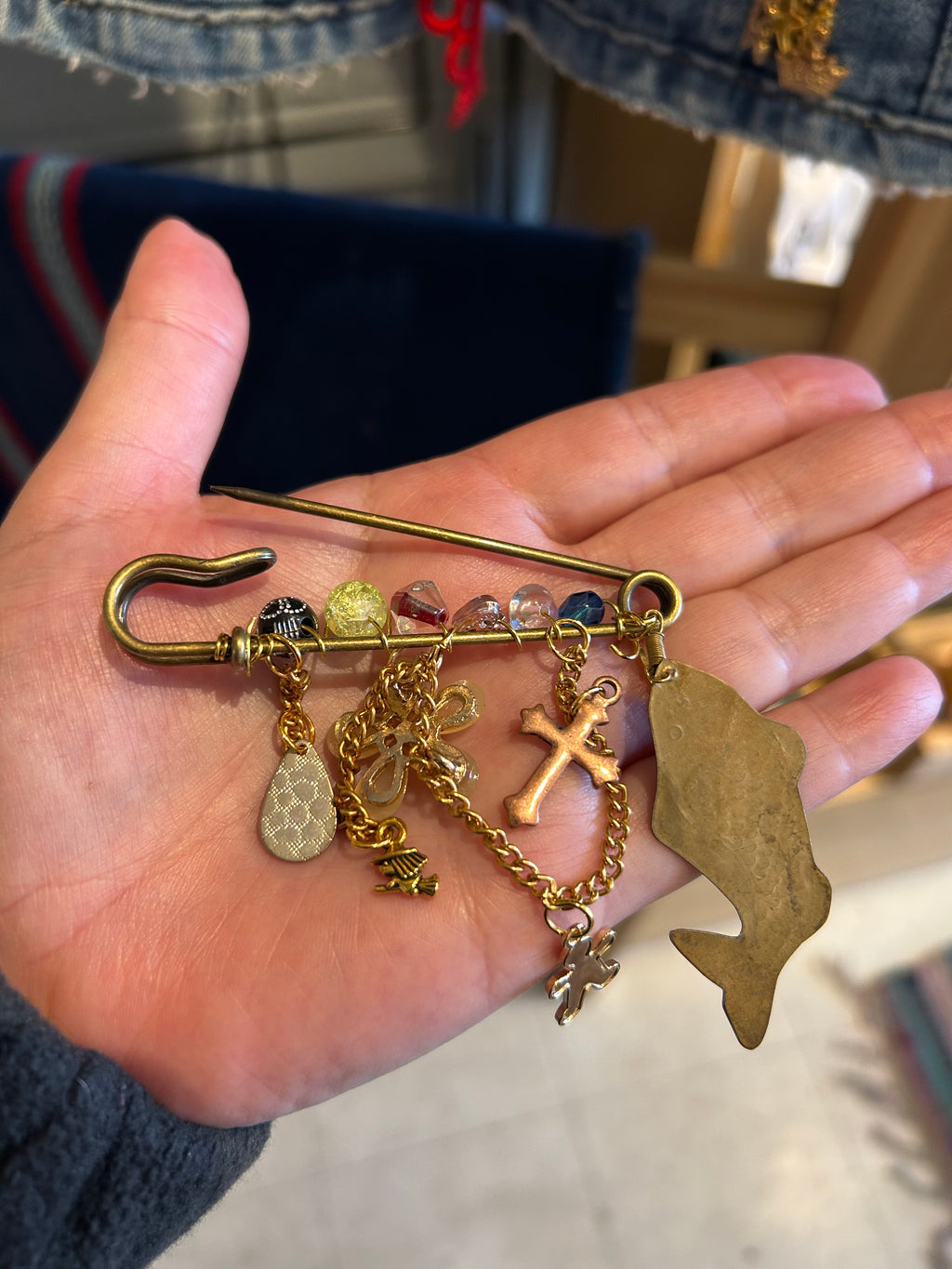 Hand holding a gold charm bracelet with various charms against a blurred background