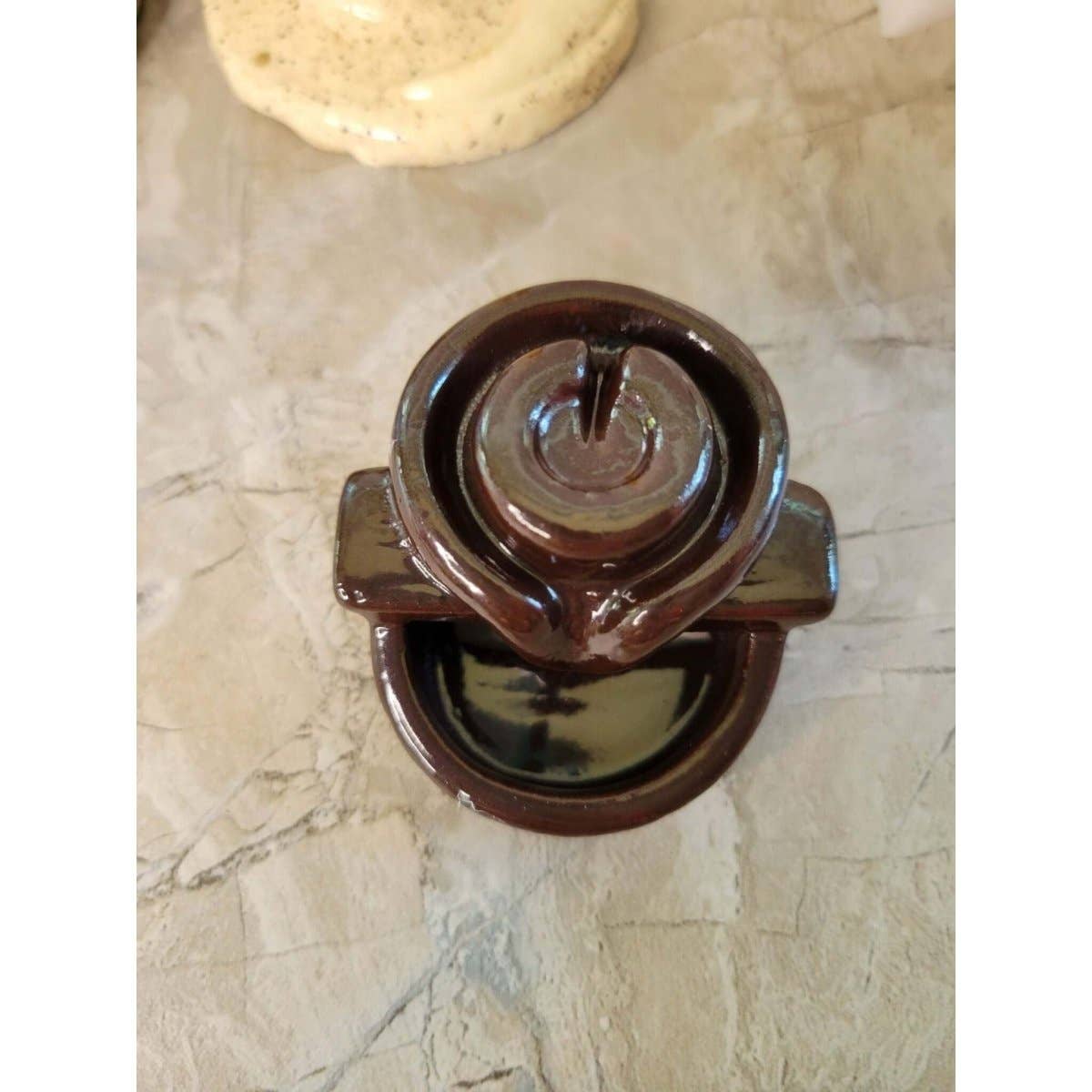 Brown ceramic back flow incense burner on a marble surface