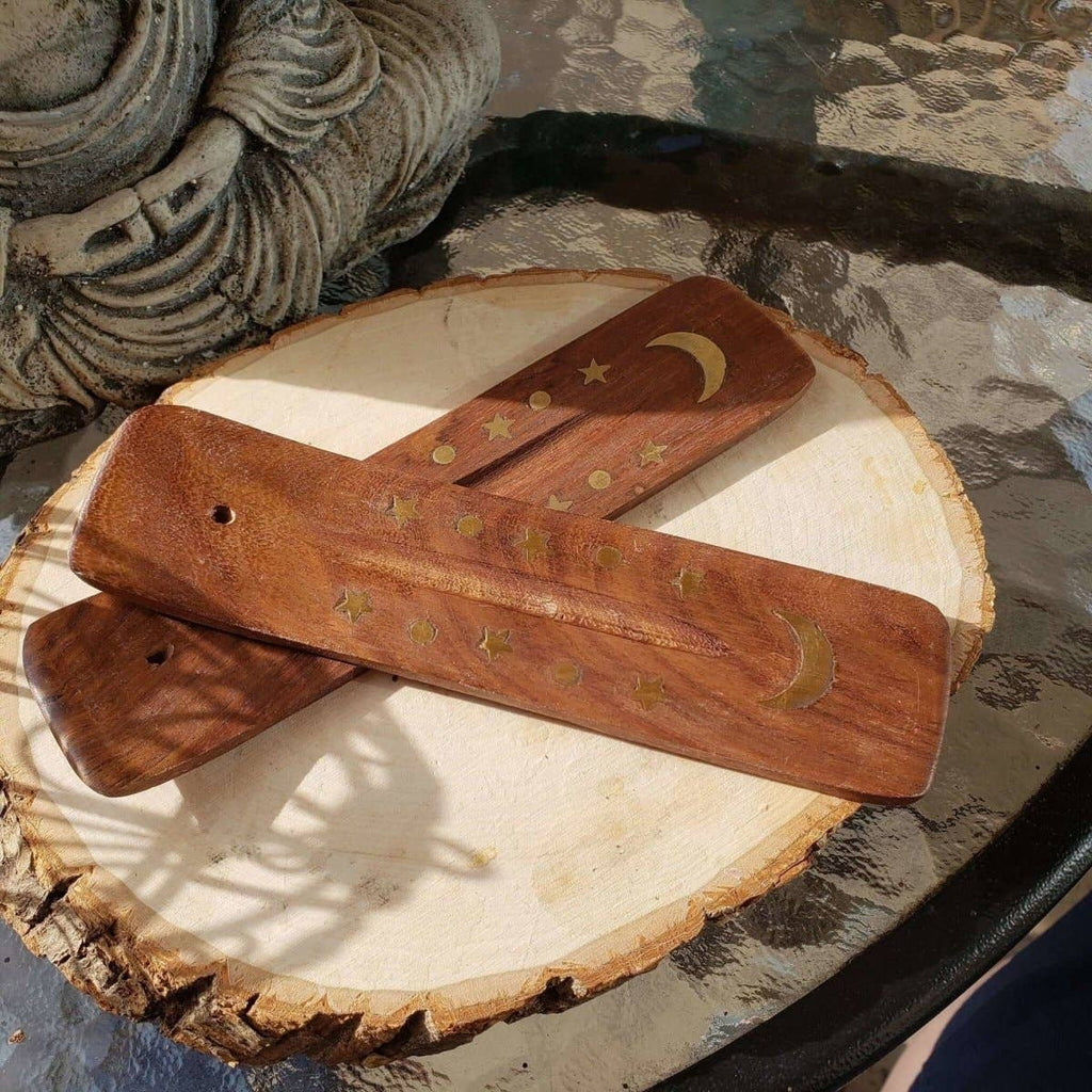 Wooden incense sticks with star and moon designs on a wooden surface.