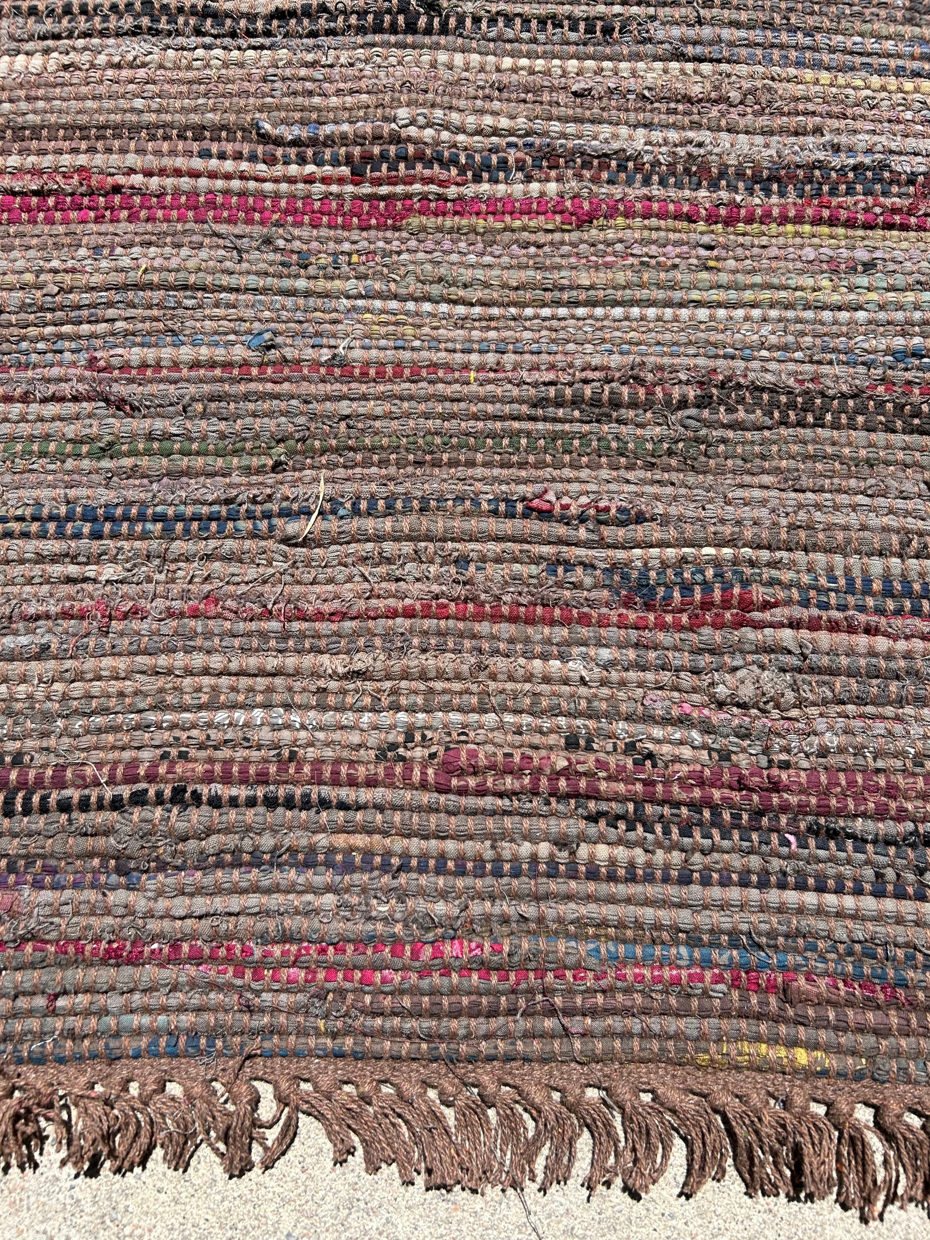 Close-up of a textured rug with multicolored stripes and fringes.