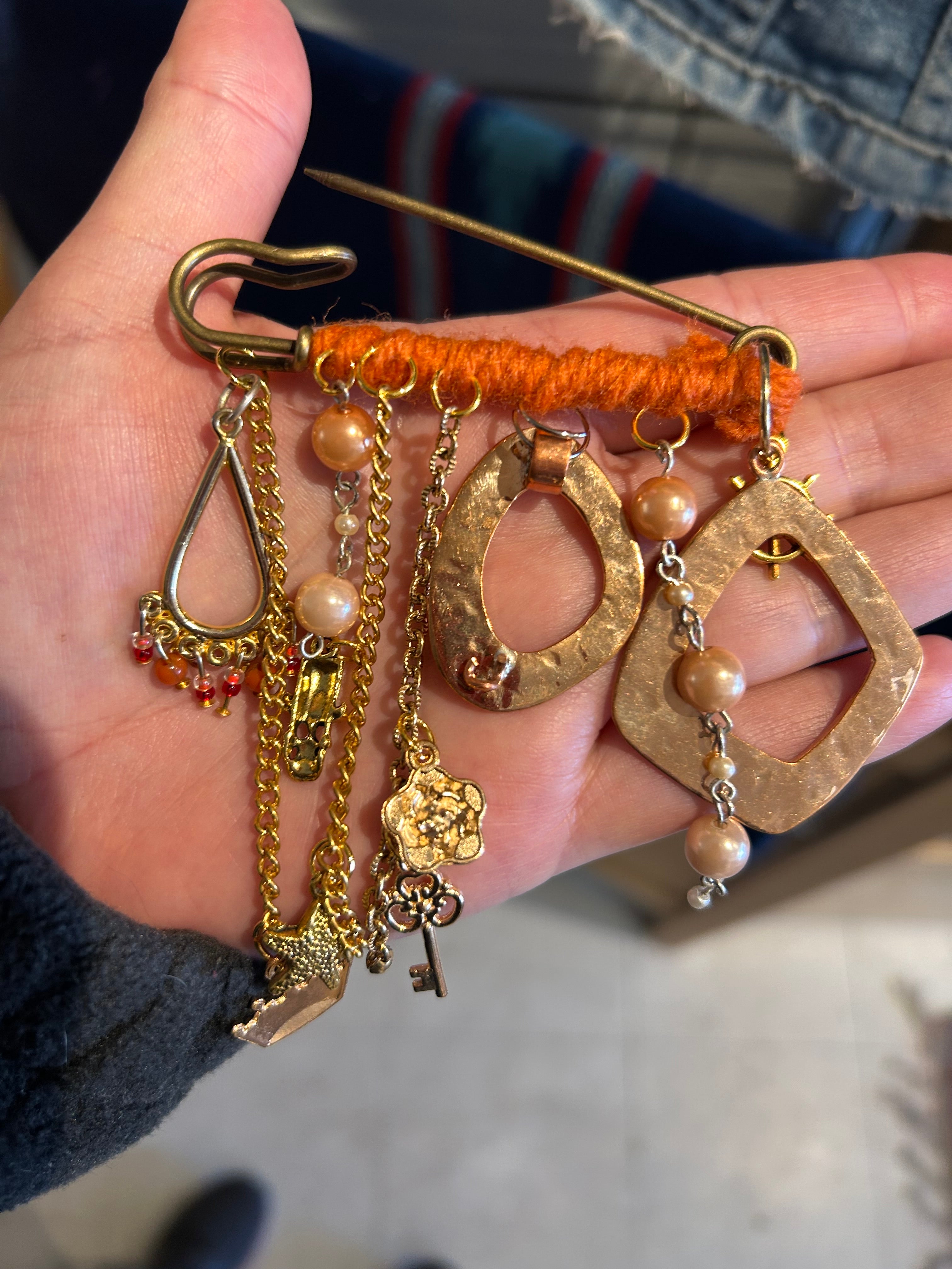 Hand holding a collection of gold jewelry with various charms and chains.