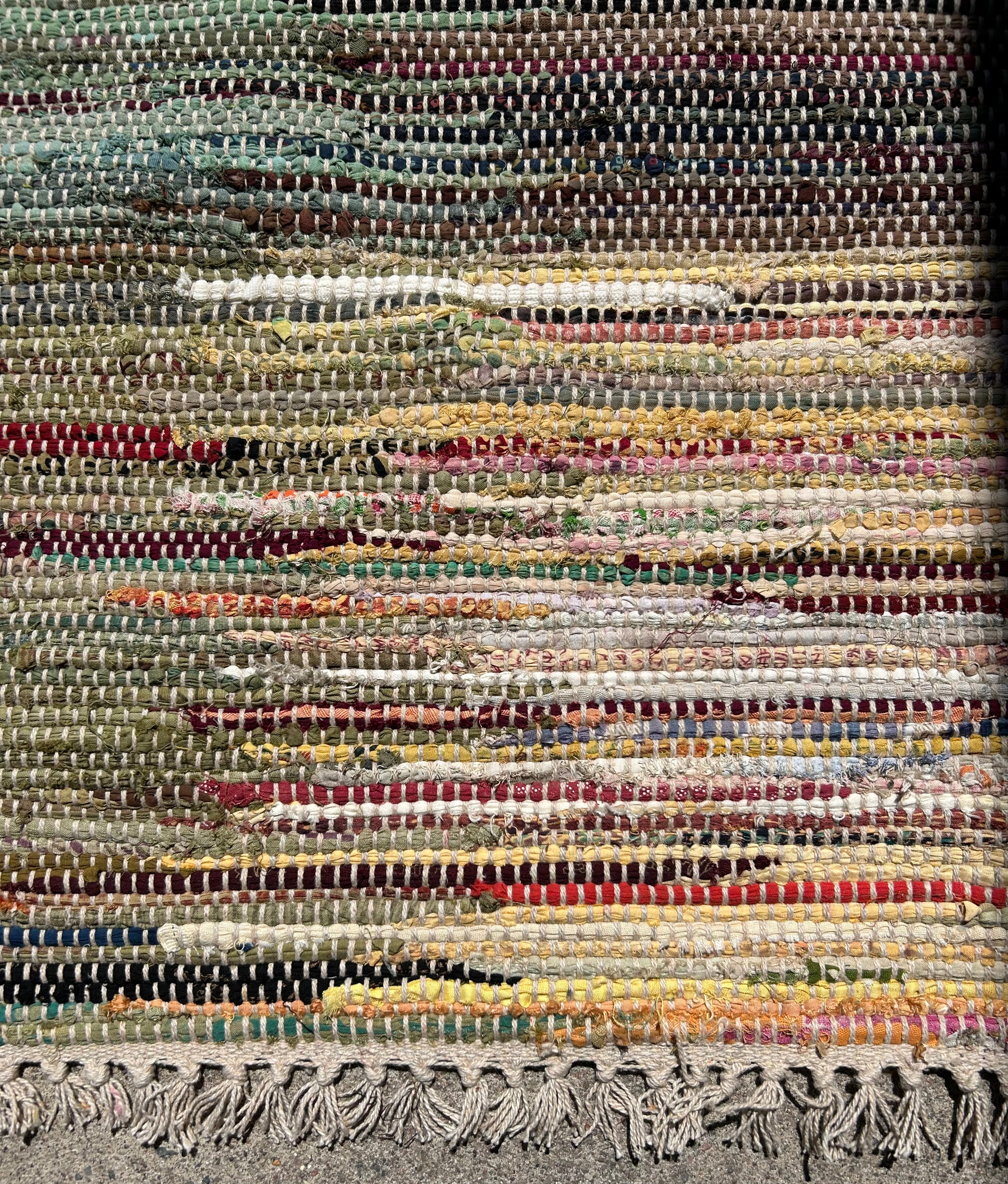 Close-up of a multicolored woven rug with fringes.