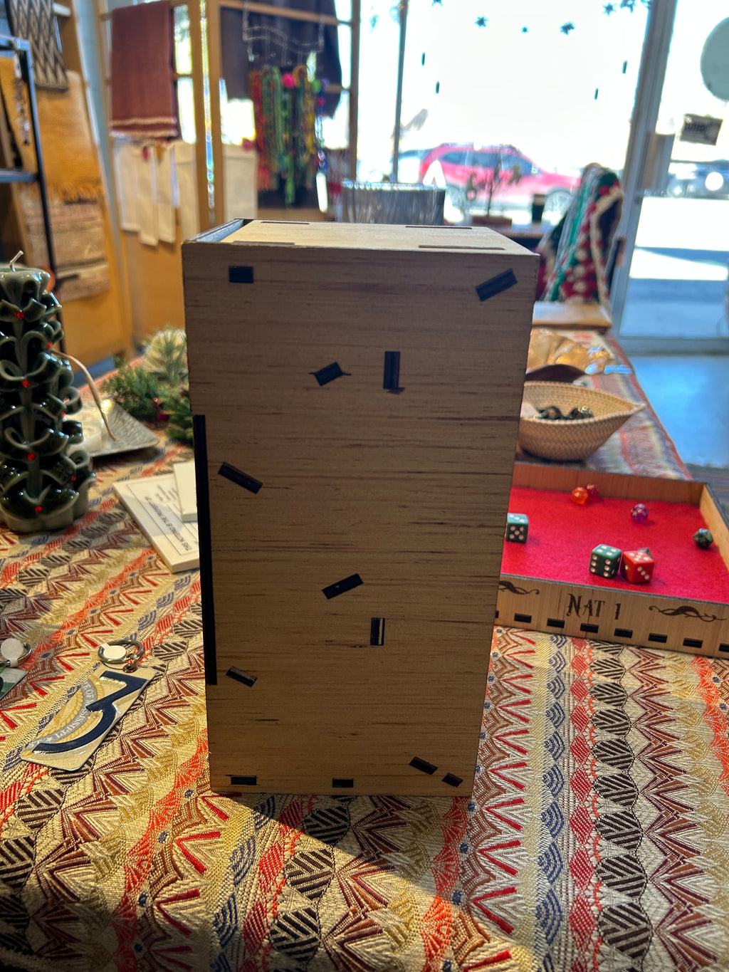 Wooden Dice Tower box side view with black markers on a patterned fabric background