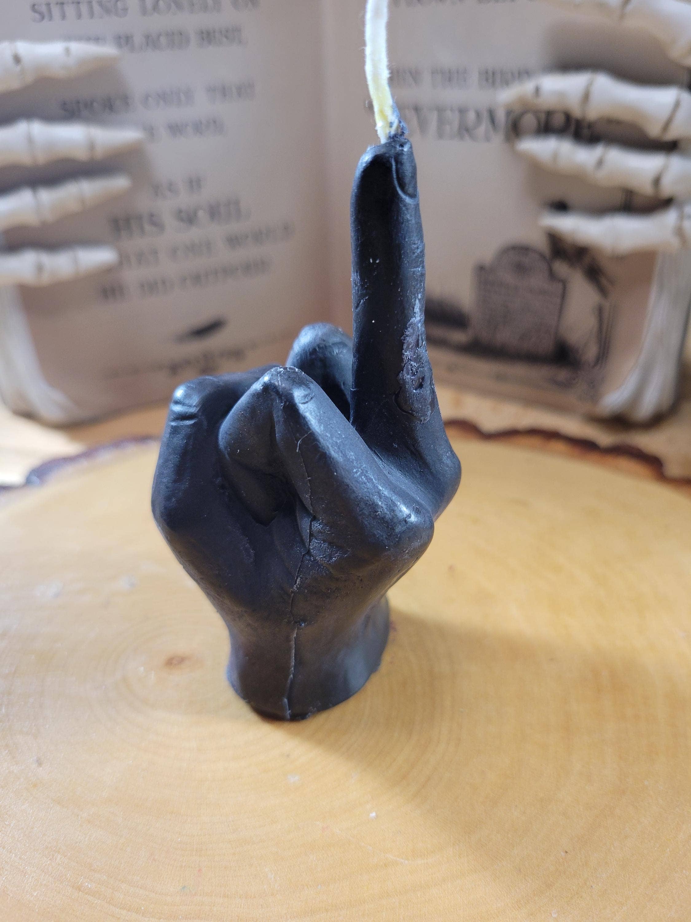 Black hand candle with middle finger gesture on a wooden surface