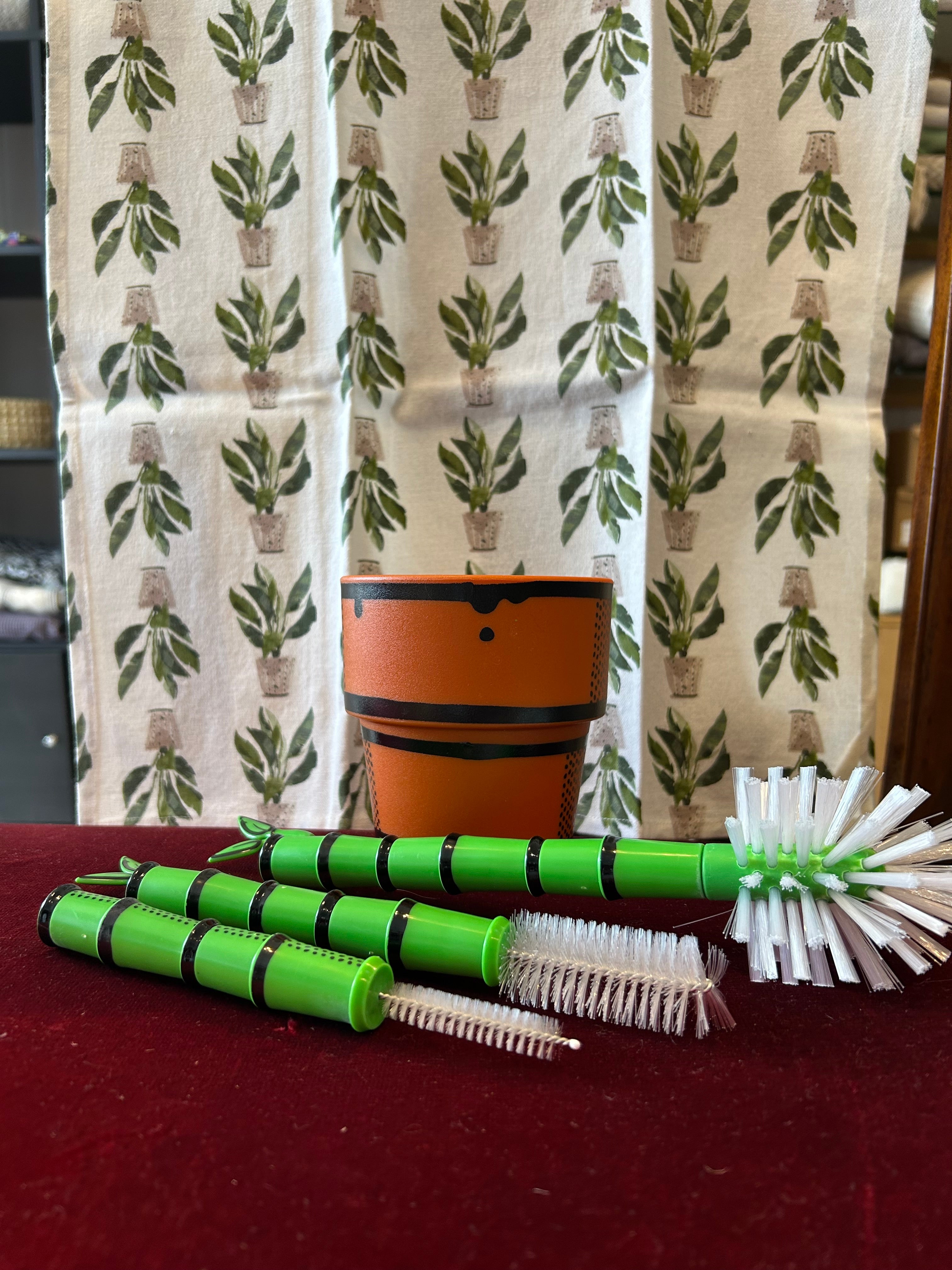 Green Bamboo Looking Bottle Brush Set with orange plant pot looking base with a Peace Lily Tea Towel by Mahogany.