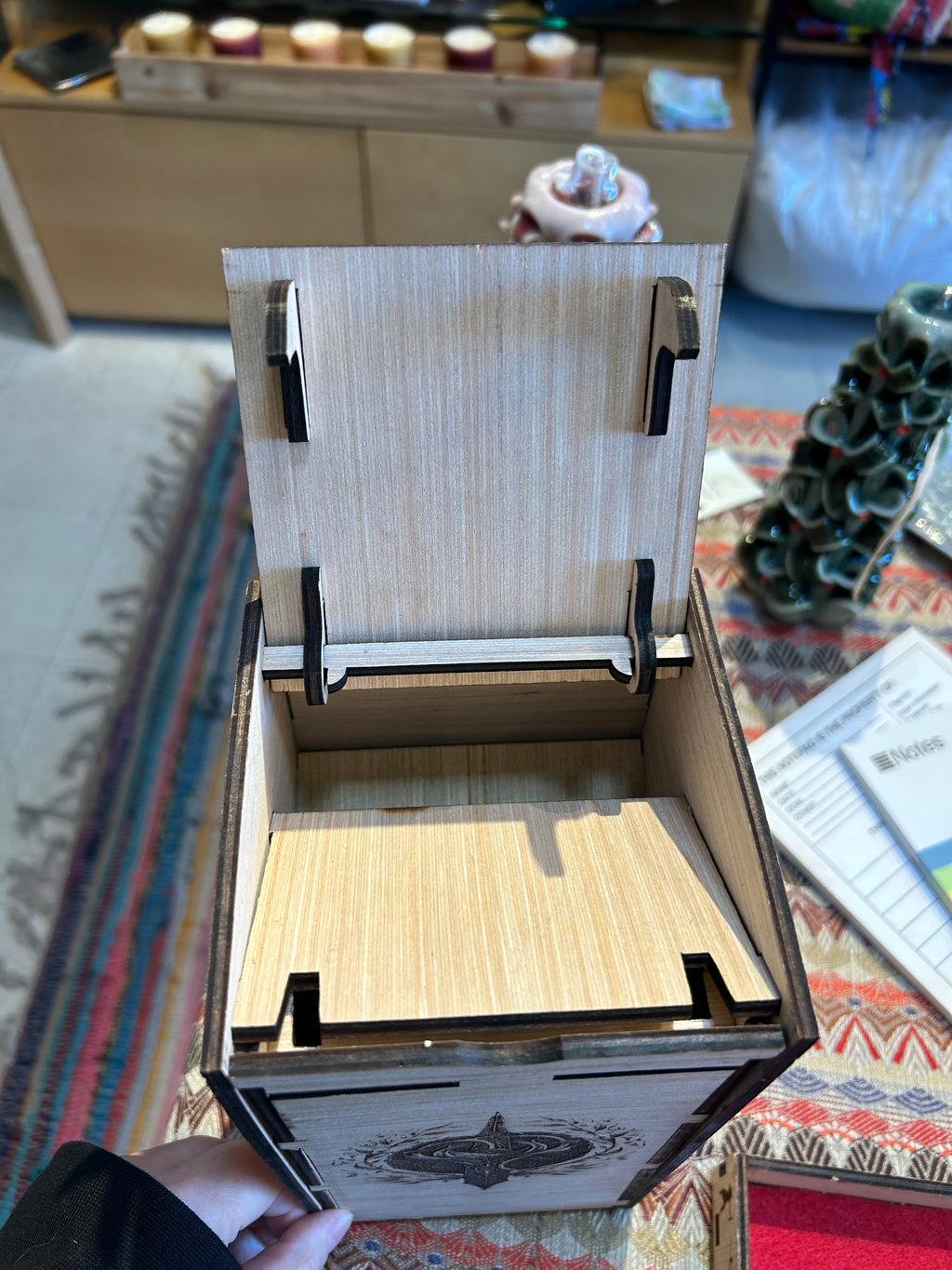 Wooden Dice Tower box with a lid being held open on a patterned surface