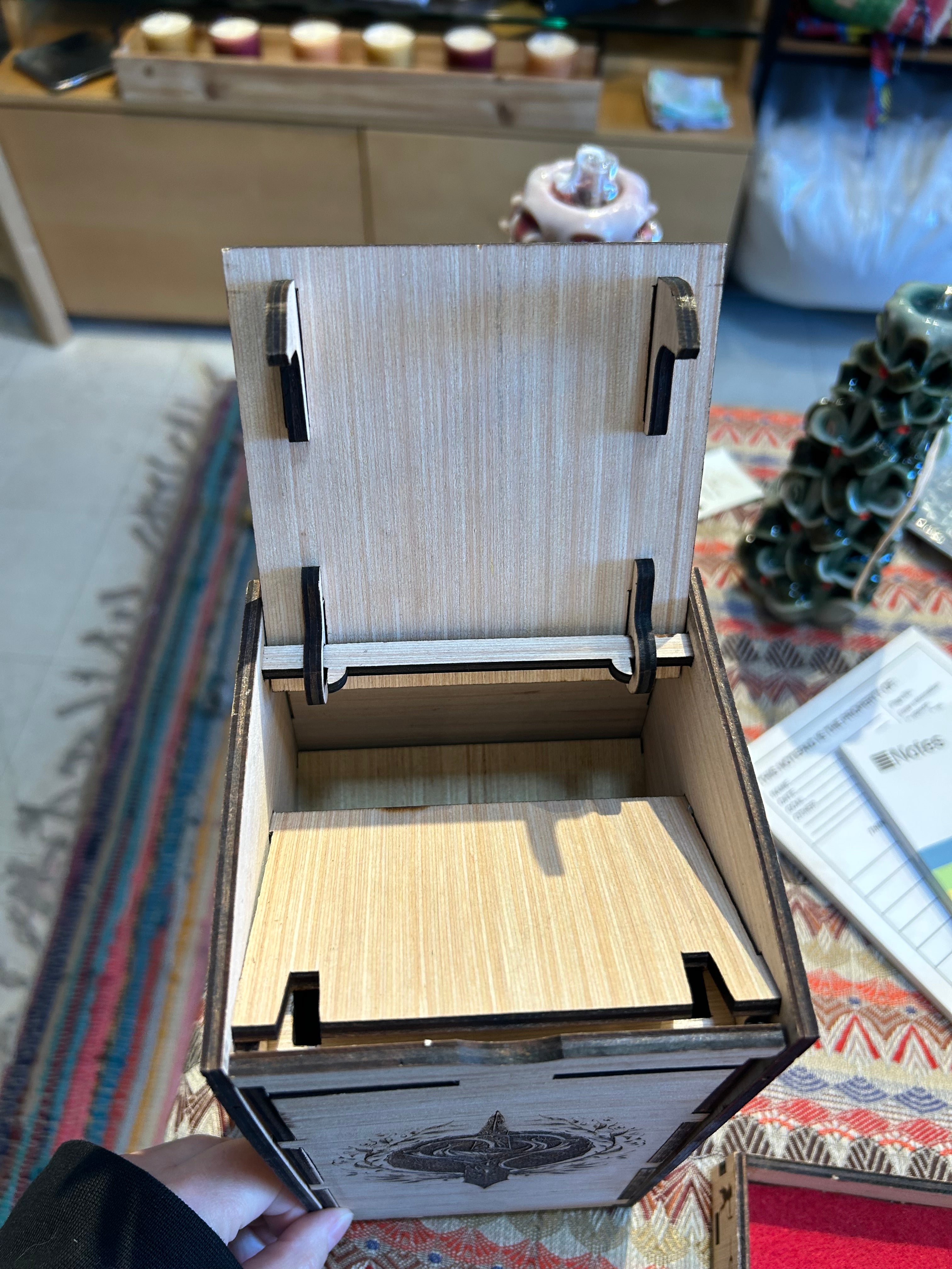 Wooden Dice Tower box with a lid being held open on a patterned surface