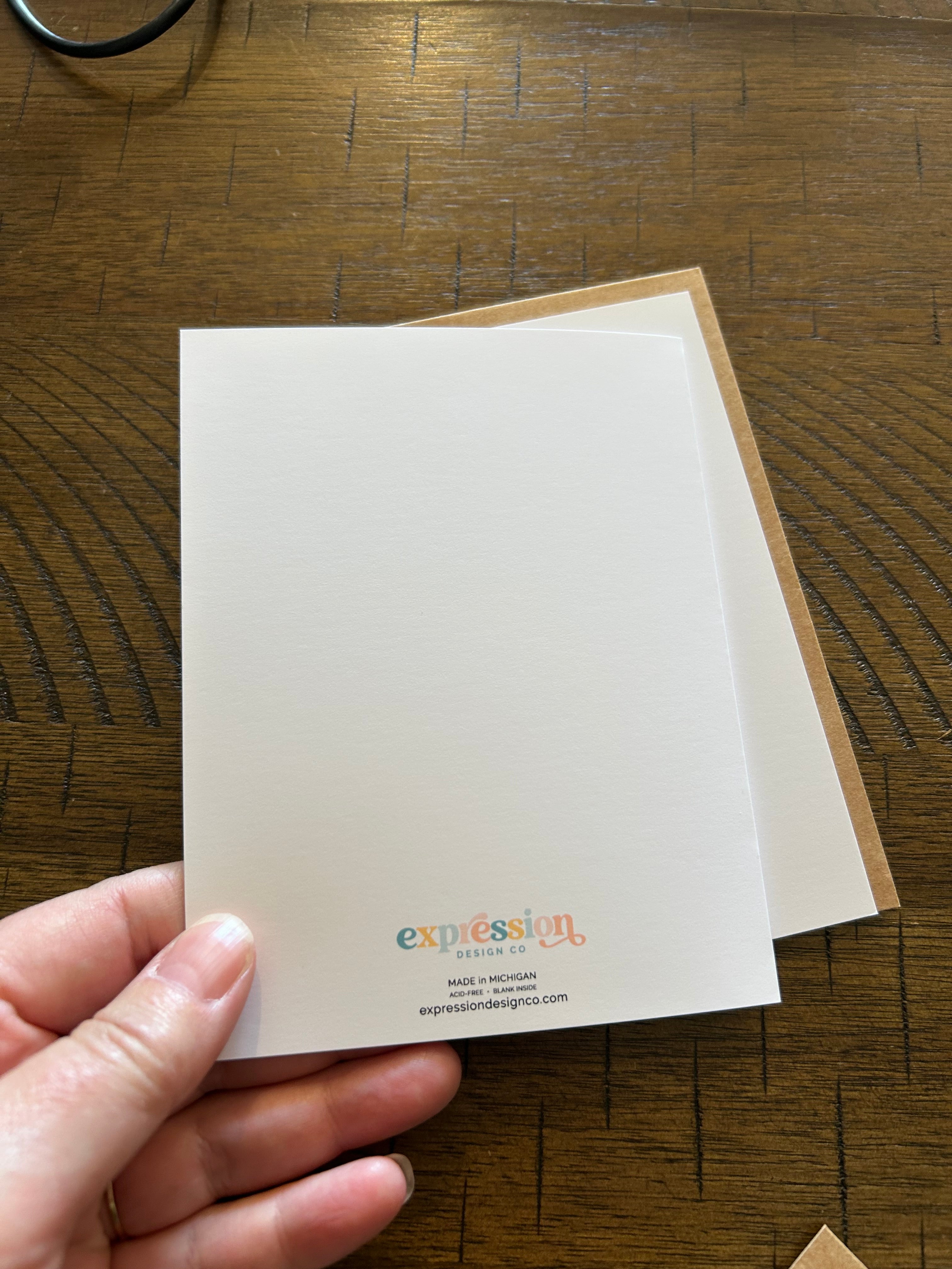 Hand holding a card with the back of Greeting card upon a wood surface