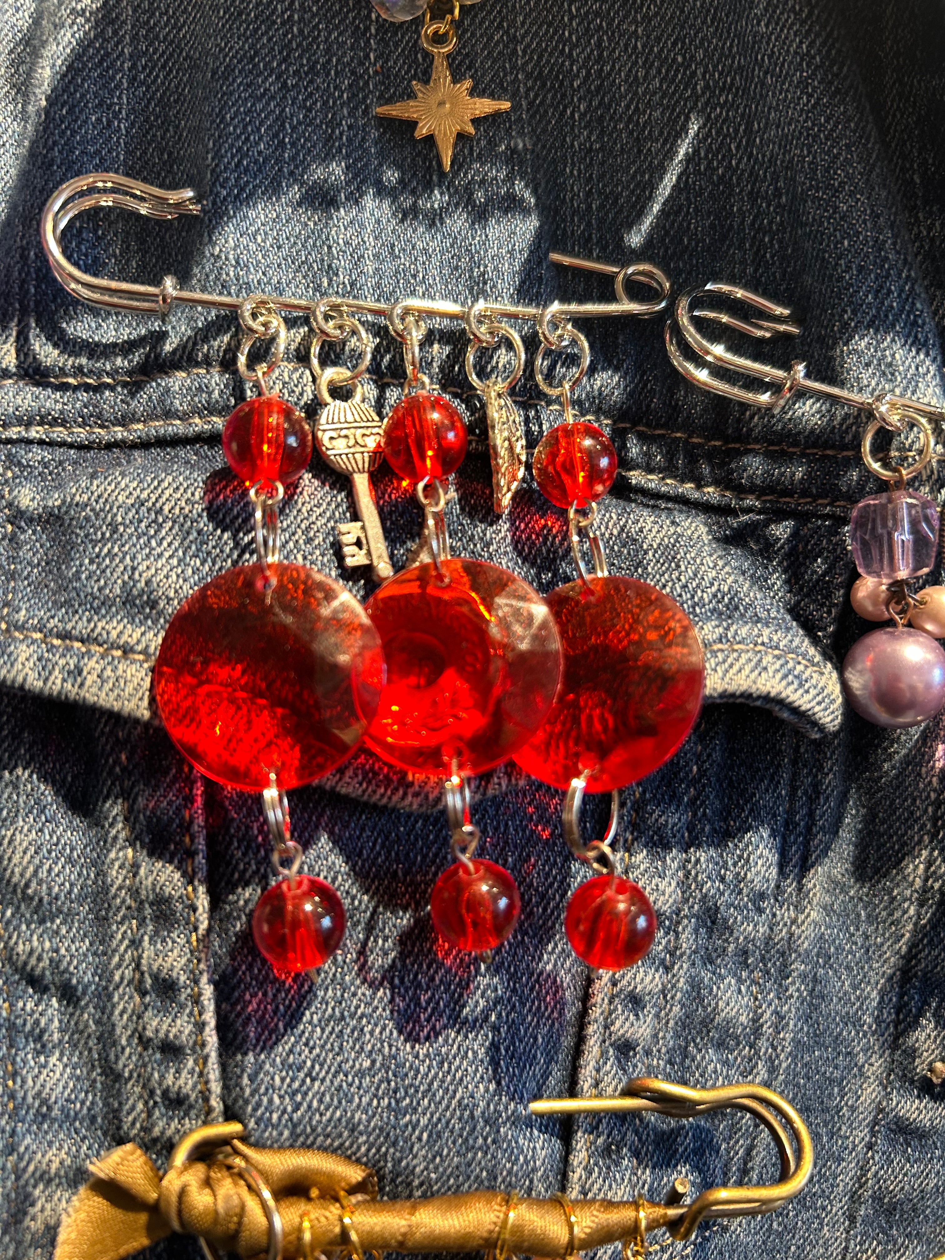 Close-up of decorative pins with red beads on a denim background
