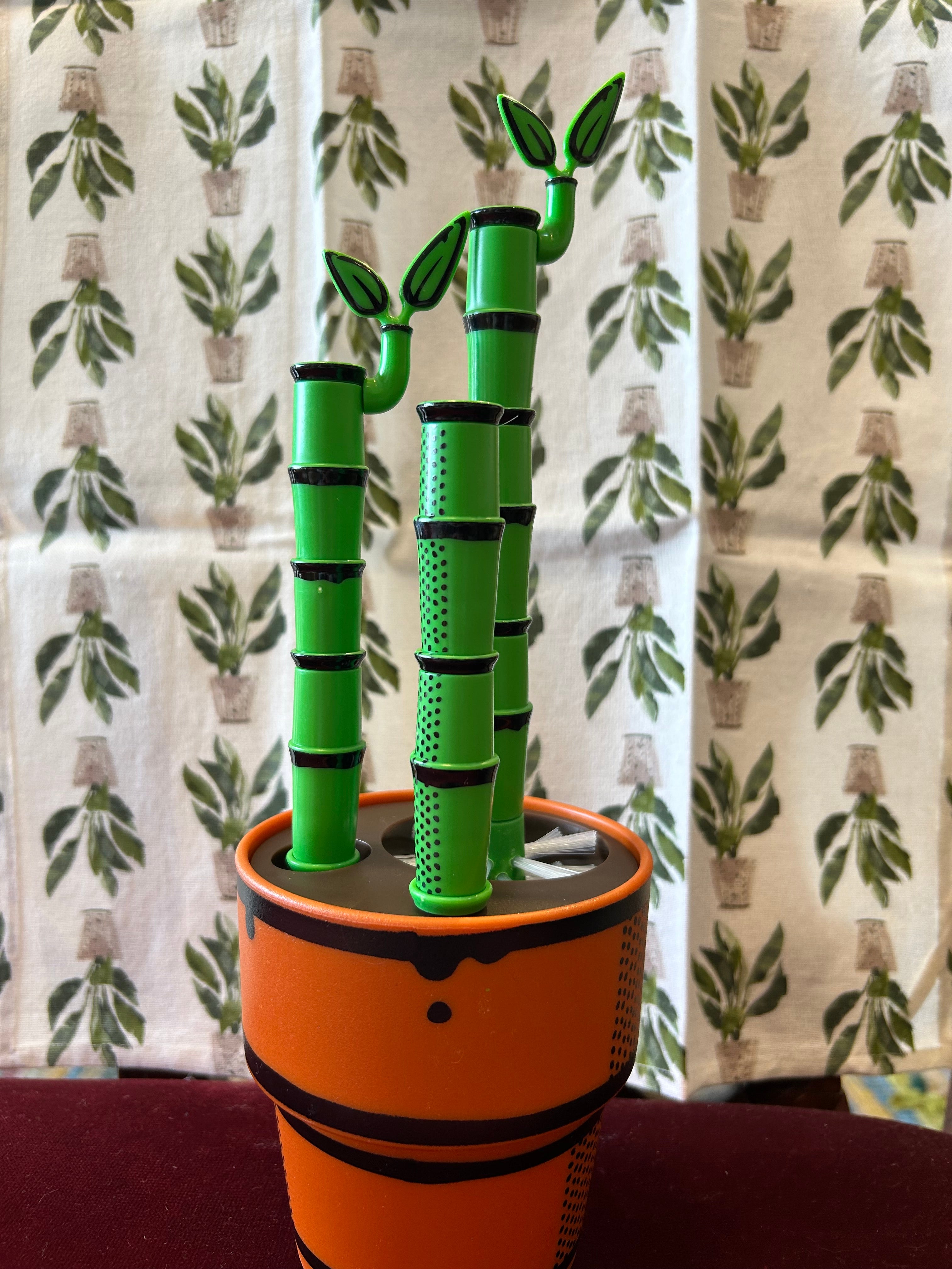 Green Bamboo Looking Bottle Brush Set with orange plant pot looking base with a Peace Lily Tea Towel by Mahogany.