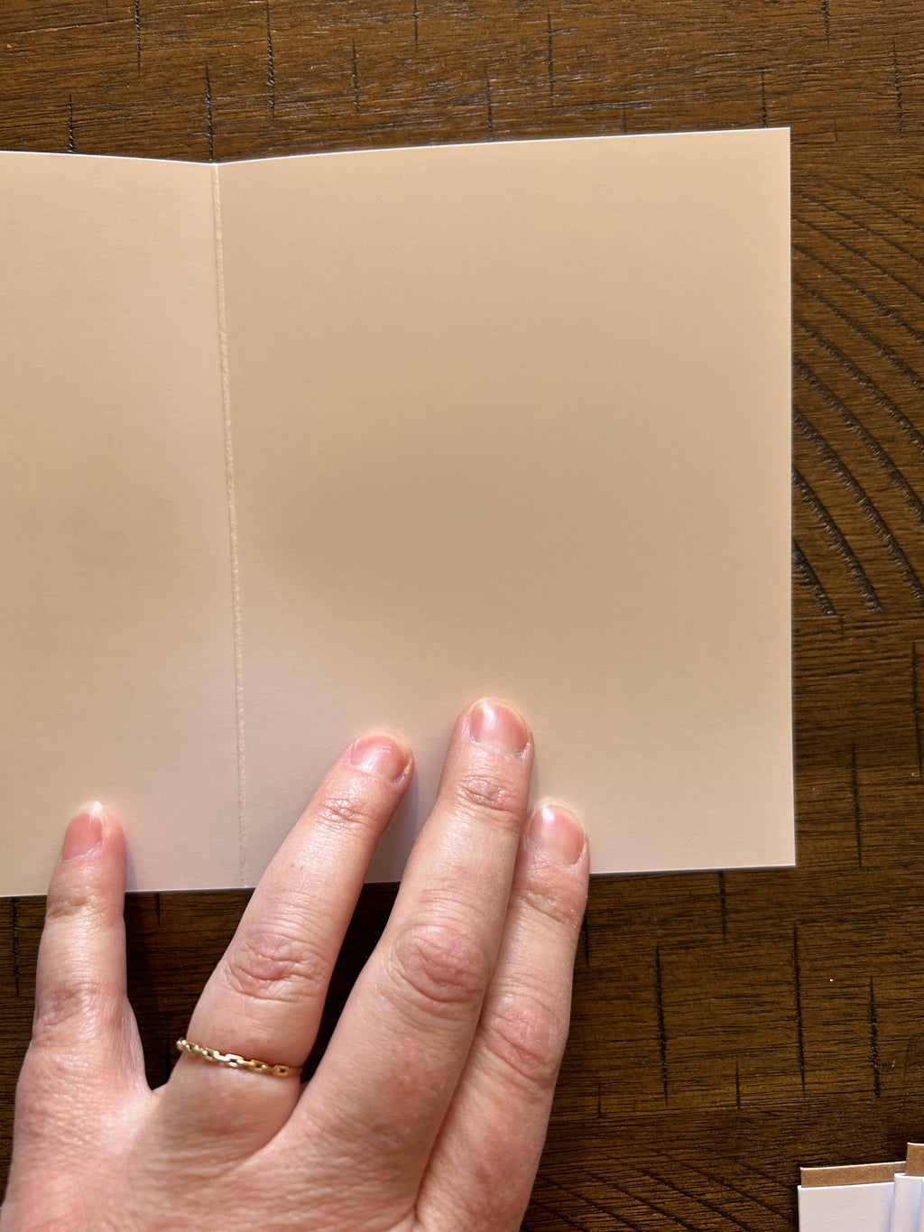 Hand holding a greeting card showing blank white inside on a wooden surface
