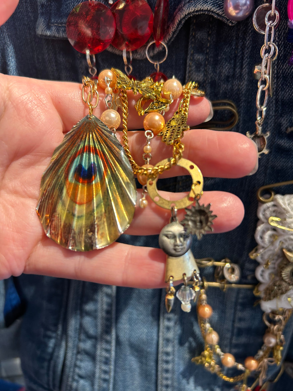 Hand holding a collection of colorful jewelry charms against a denim background