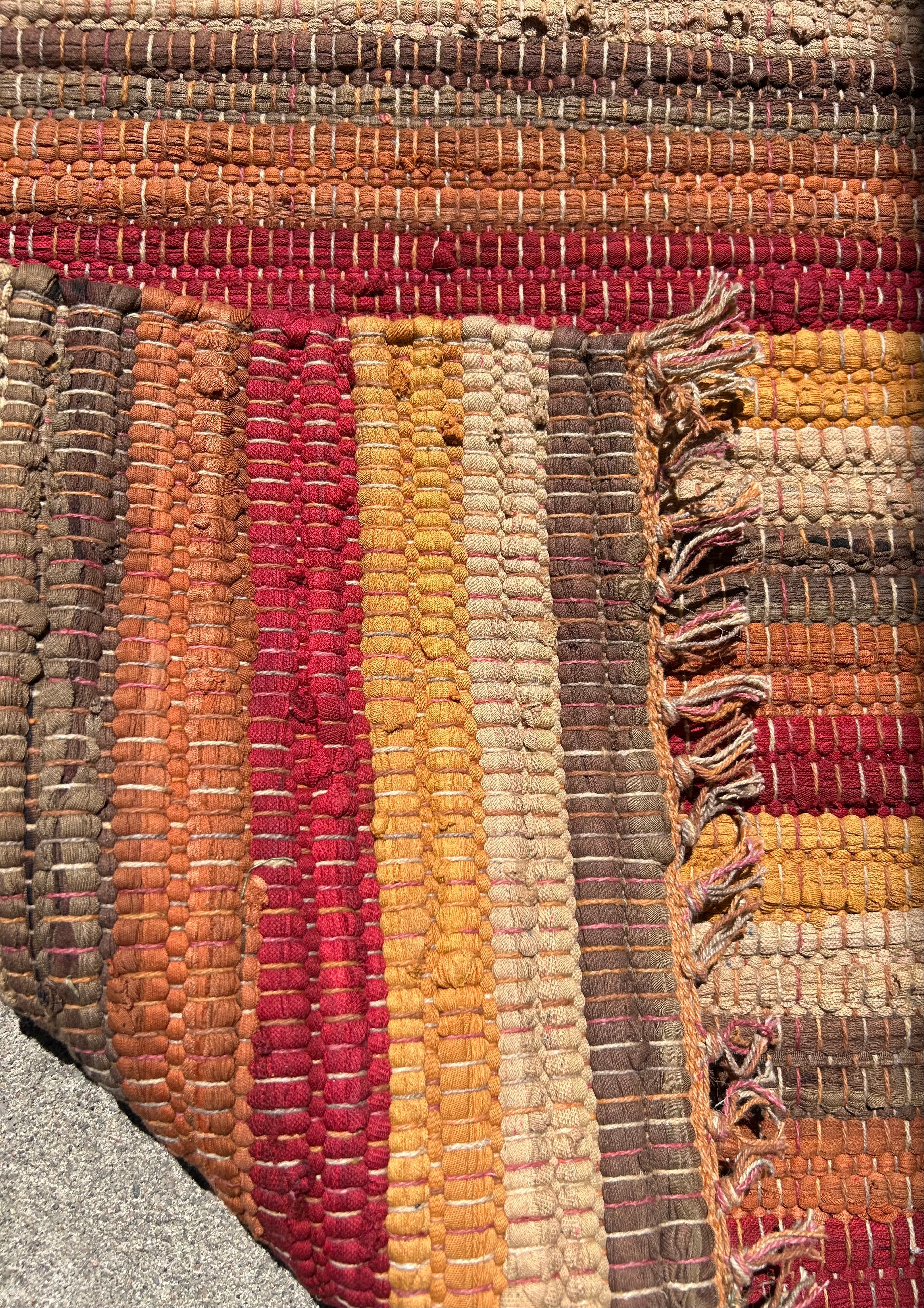 Close-up of a textured, multicolored rug with a fringe edge. Showing Back same as front.