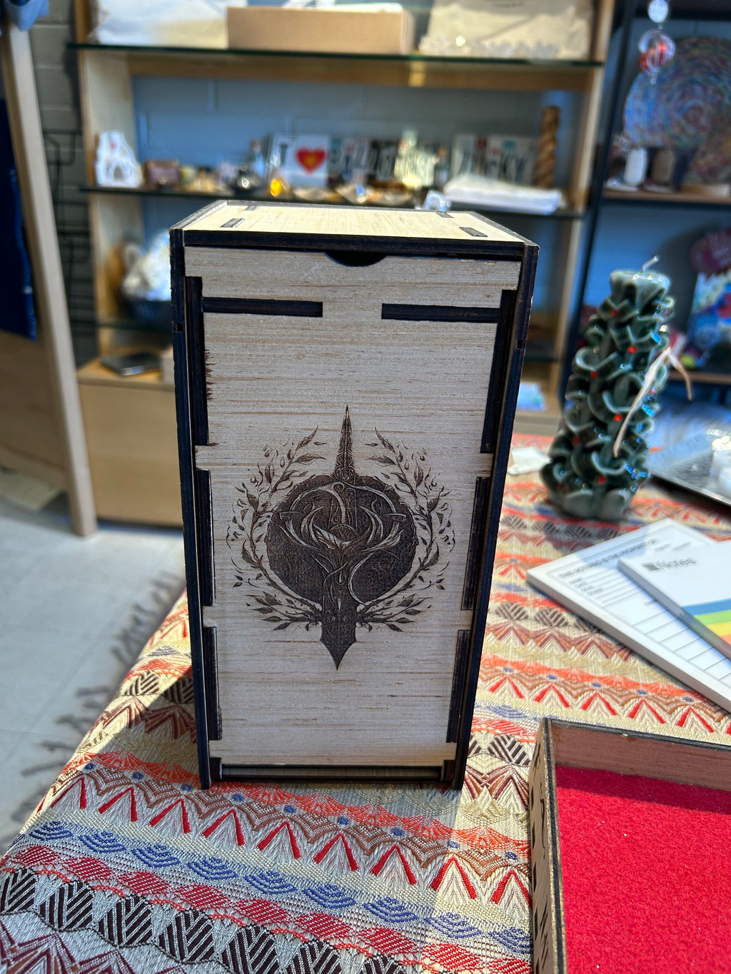 Wooden Dice Tower box with a decorative design on a patterned surface