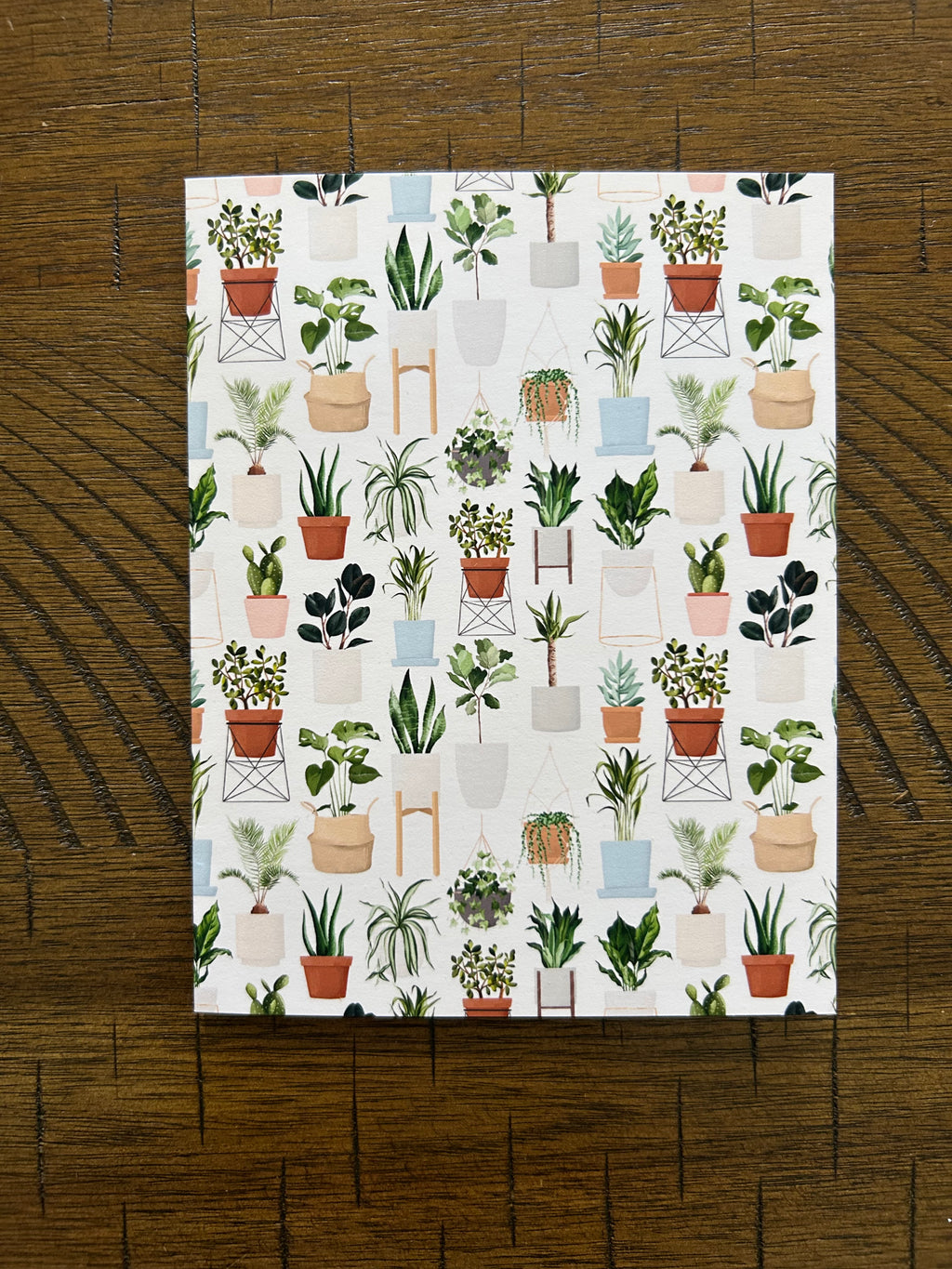Patterned greeting card with plant designs on a wooden surface