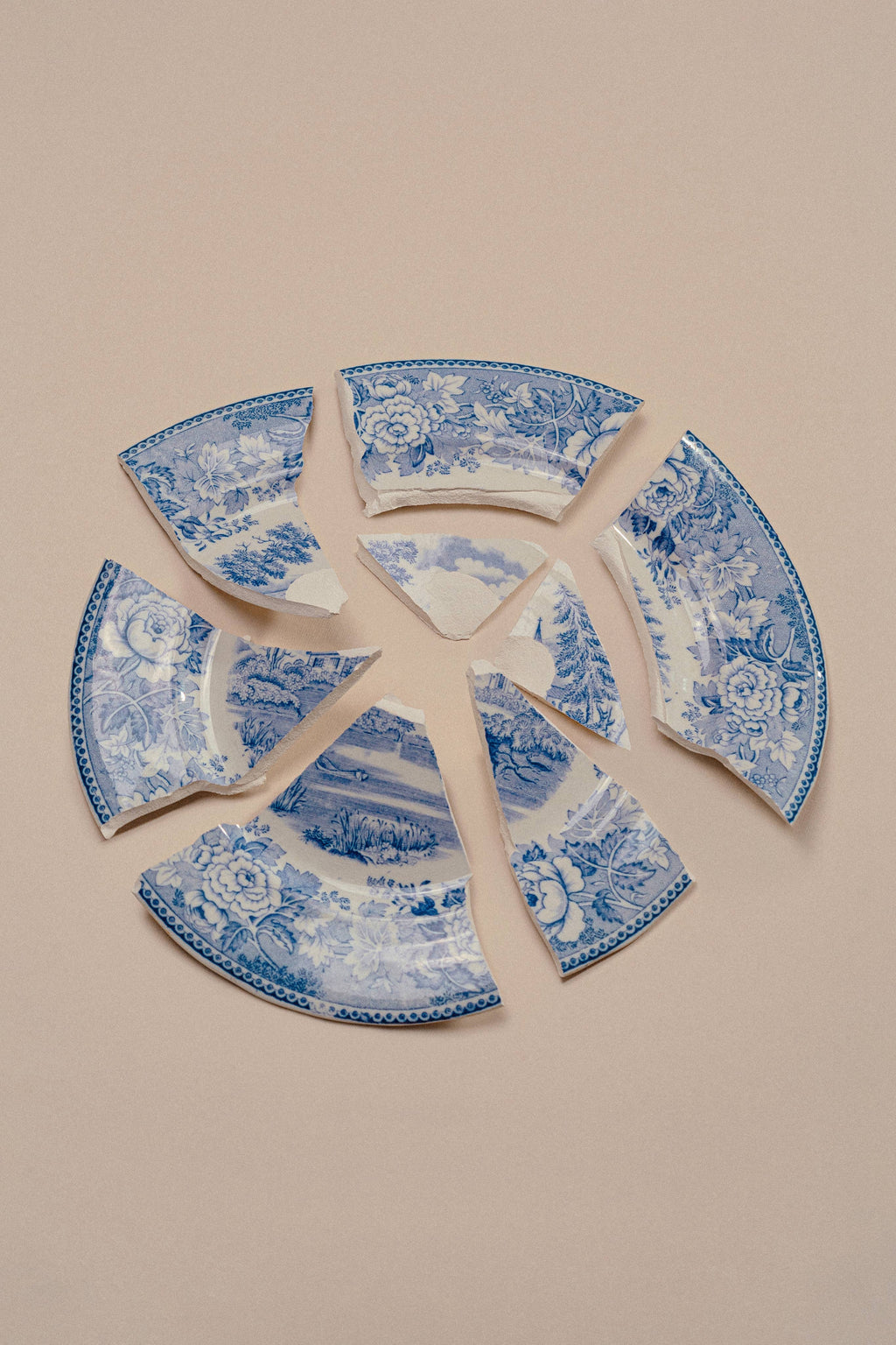 Broken blue and white ceramic plate on a beige background