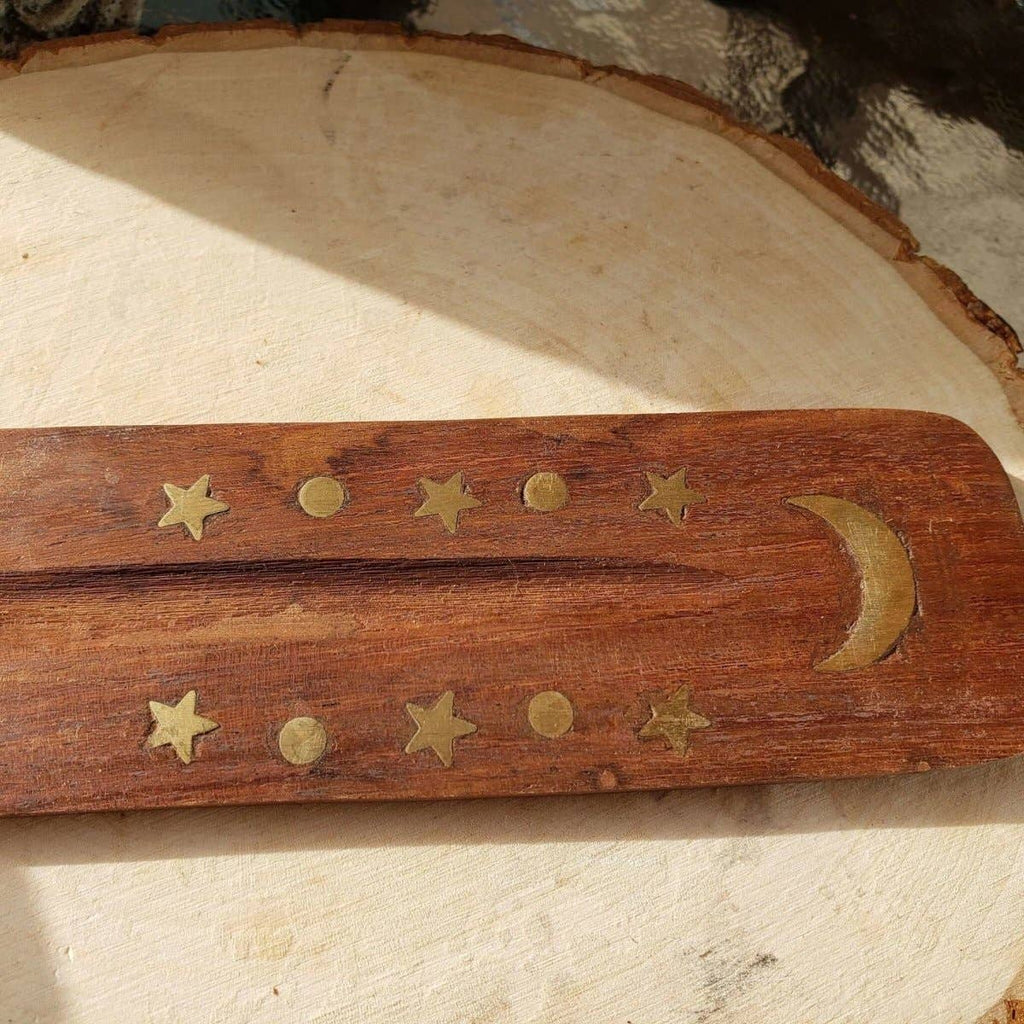 Wooden stick with brass stars and moon on a stone surface