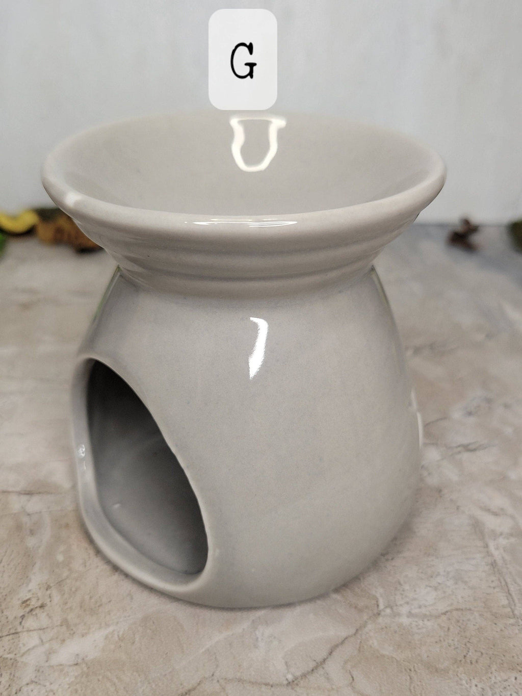 Gray ceramic oil burner on a textured surface with a blurred background