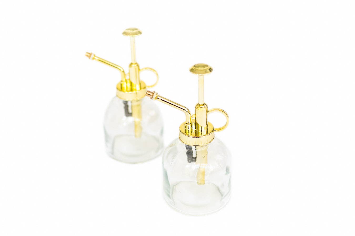 Two clear glass bottles with gold plastic nozzles on a white background