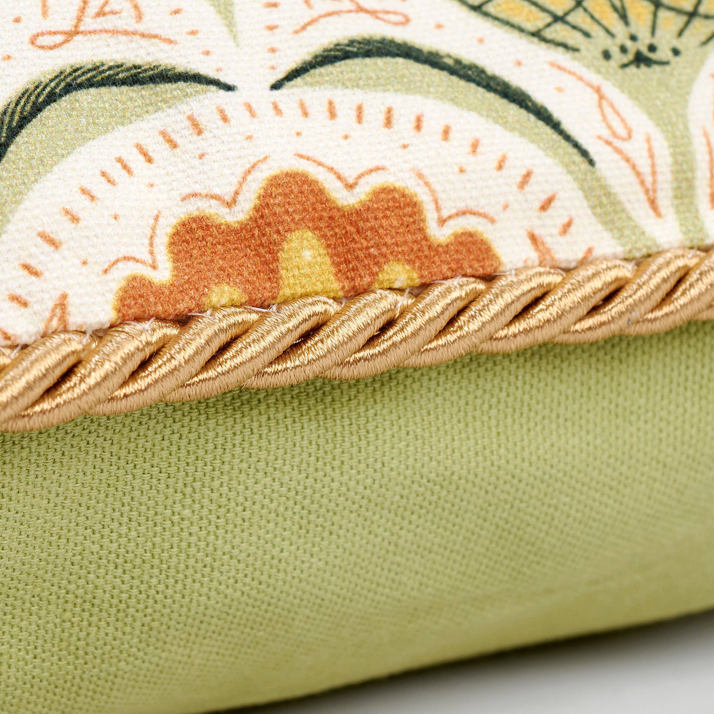 Close-up of a green fabric product with embroidered floral design and gold trim.