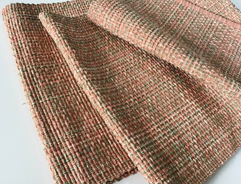 Textured table runner with a pink and green pattern on a light gray background