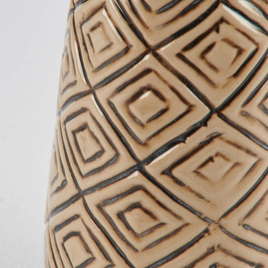 Close-up of a textured ceramic vase with geometric pattern on a light gray background